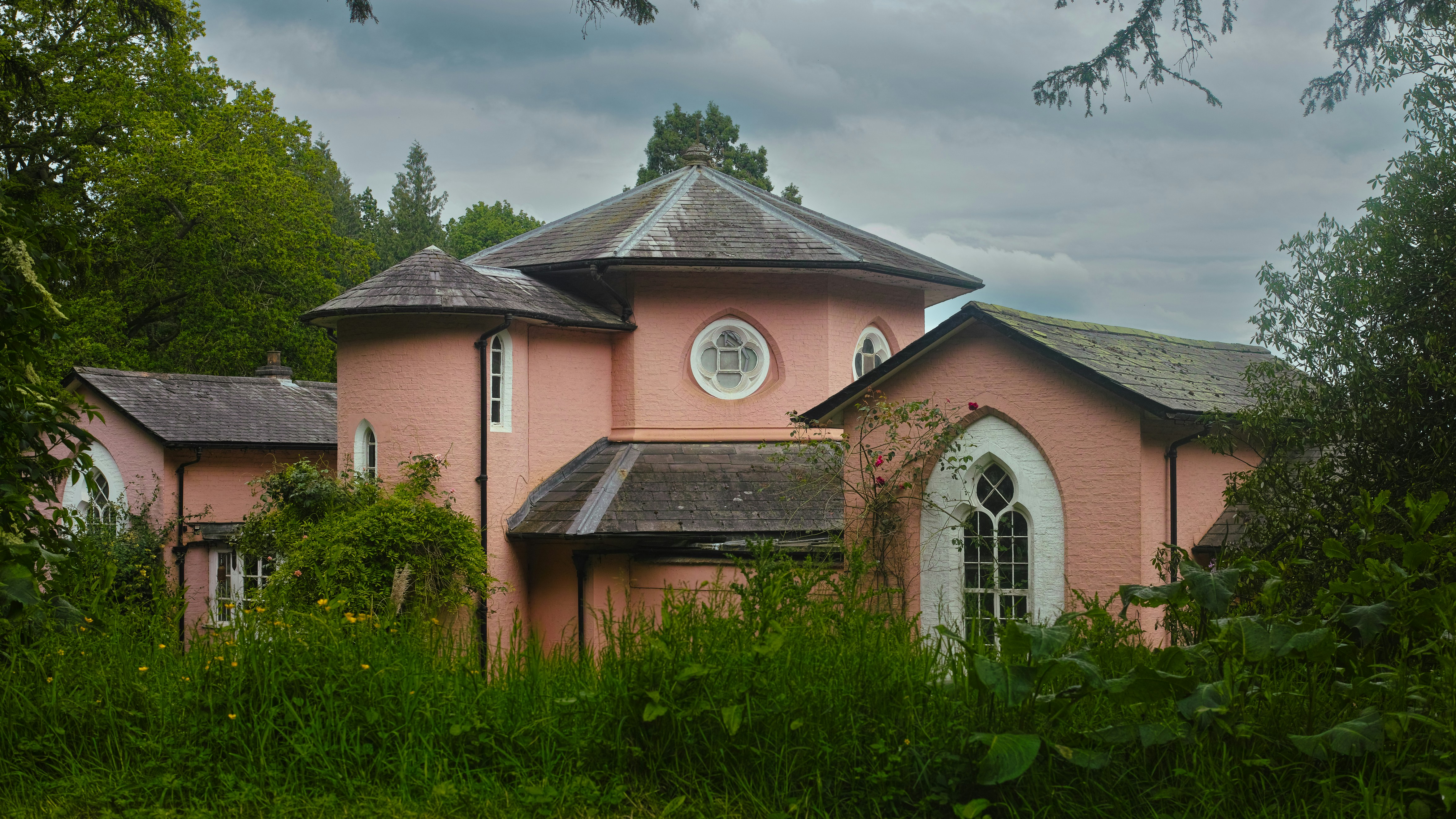a pink house with a white window and a round window