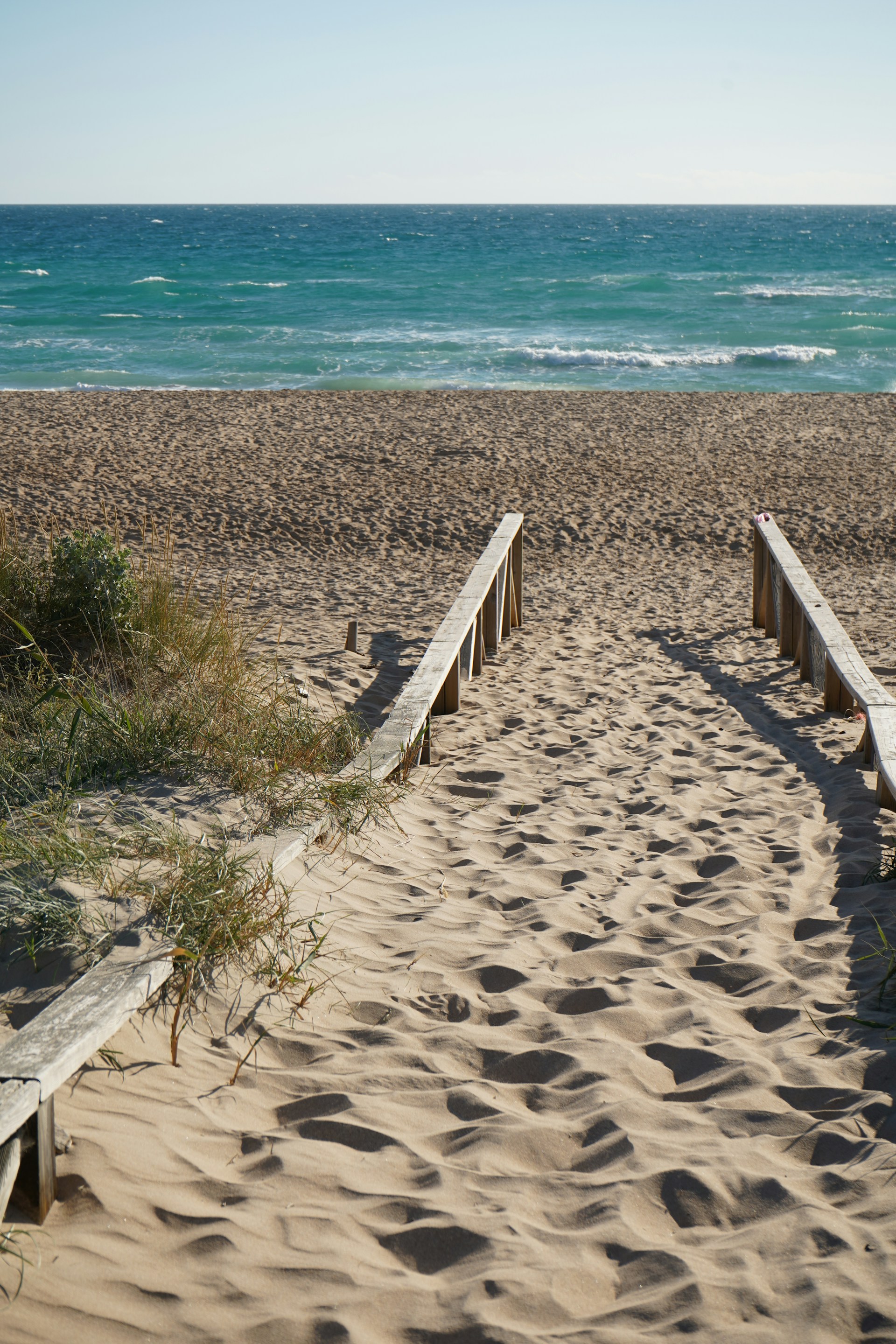 two wooden benches sitting on top of a sandy beach