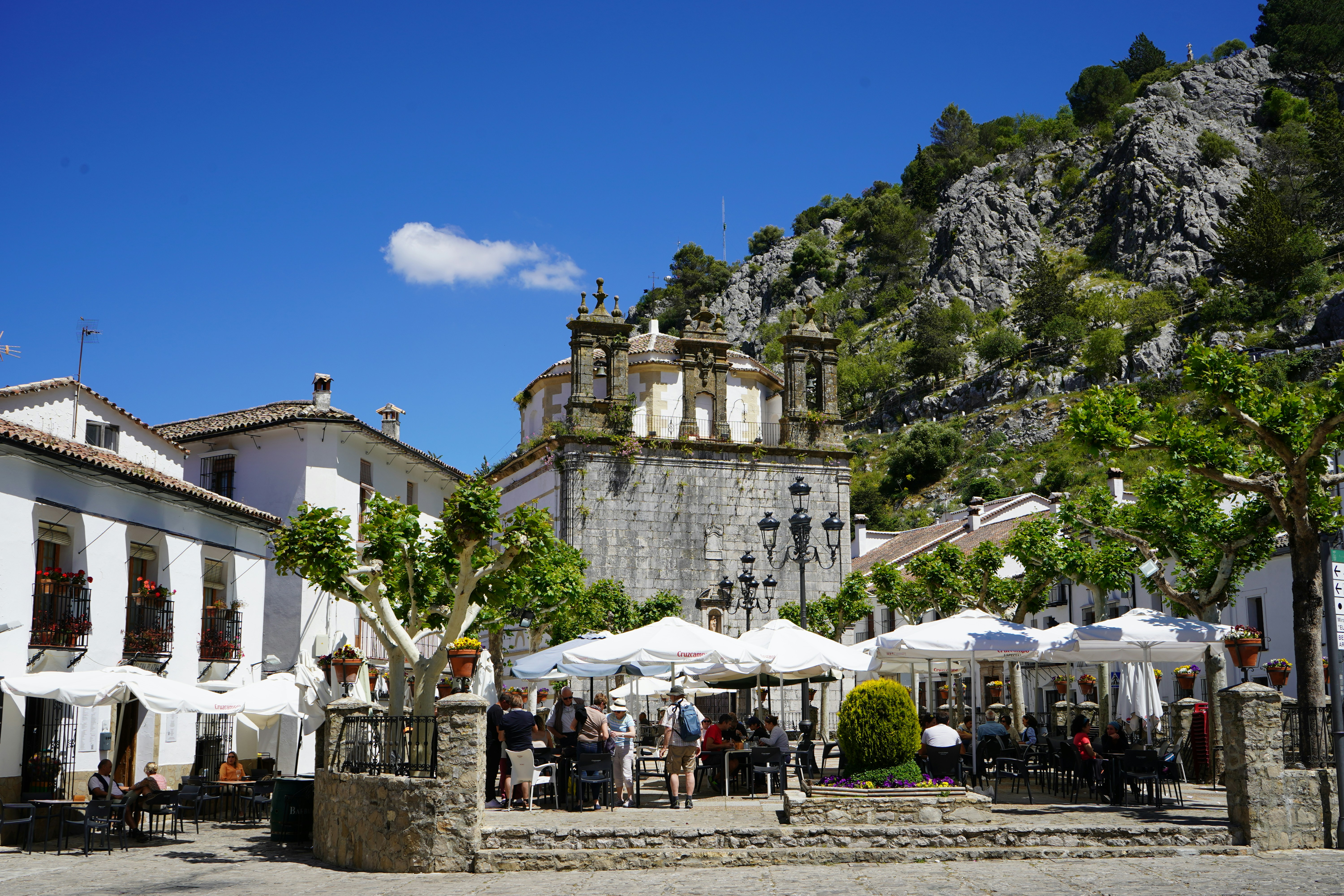 um grupo de pessoas sentadas em mesas sob guarda-chuvas