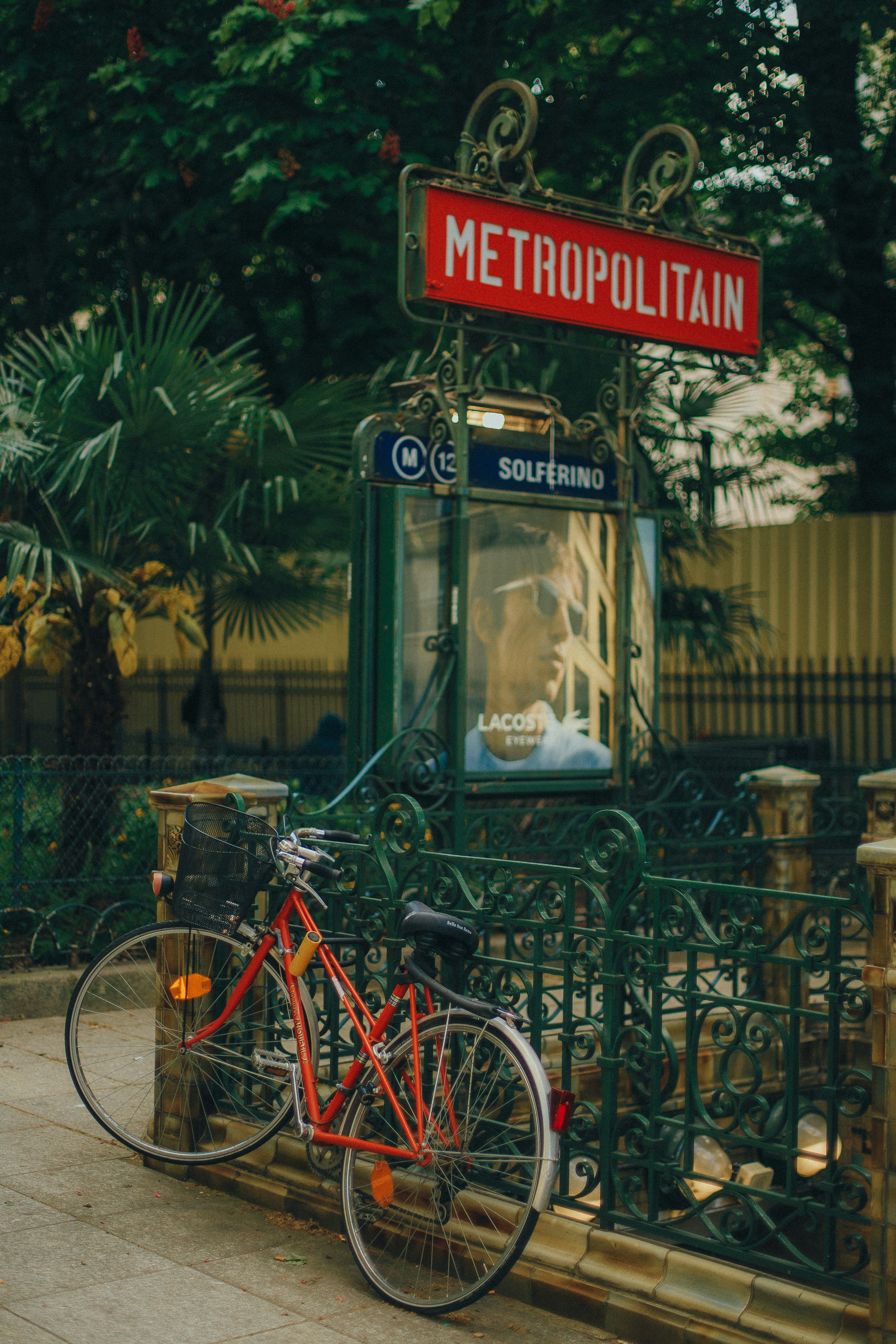 a red bike parked next to a metal fence