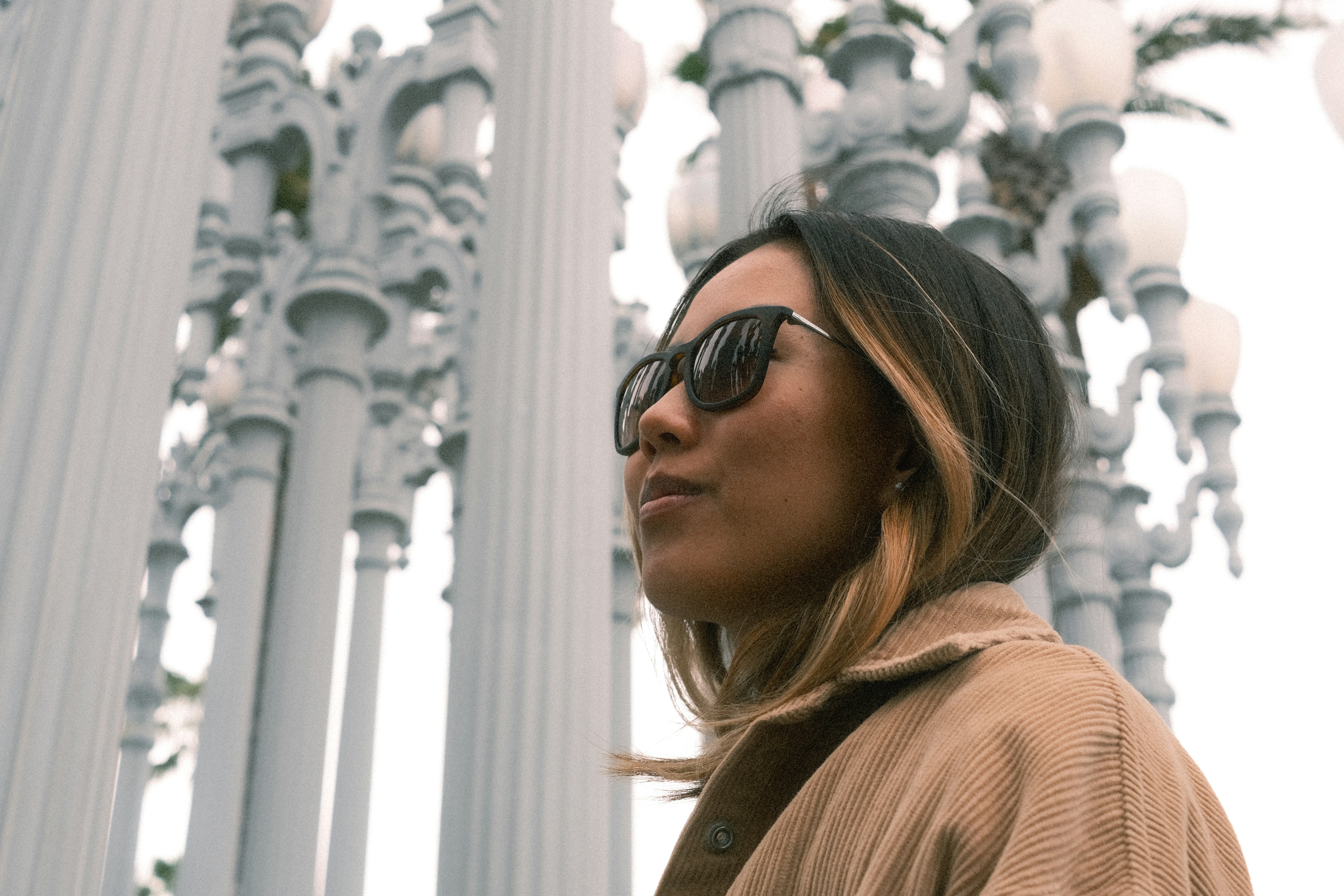 a woman wearing sunglasses standing in front of a bunch of white poles