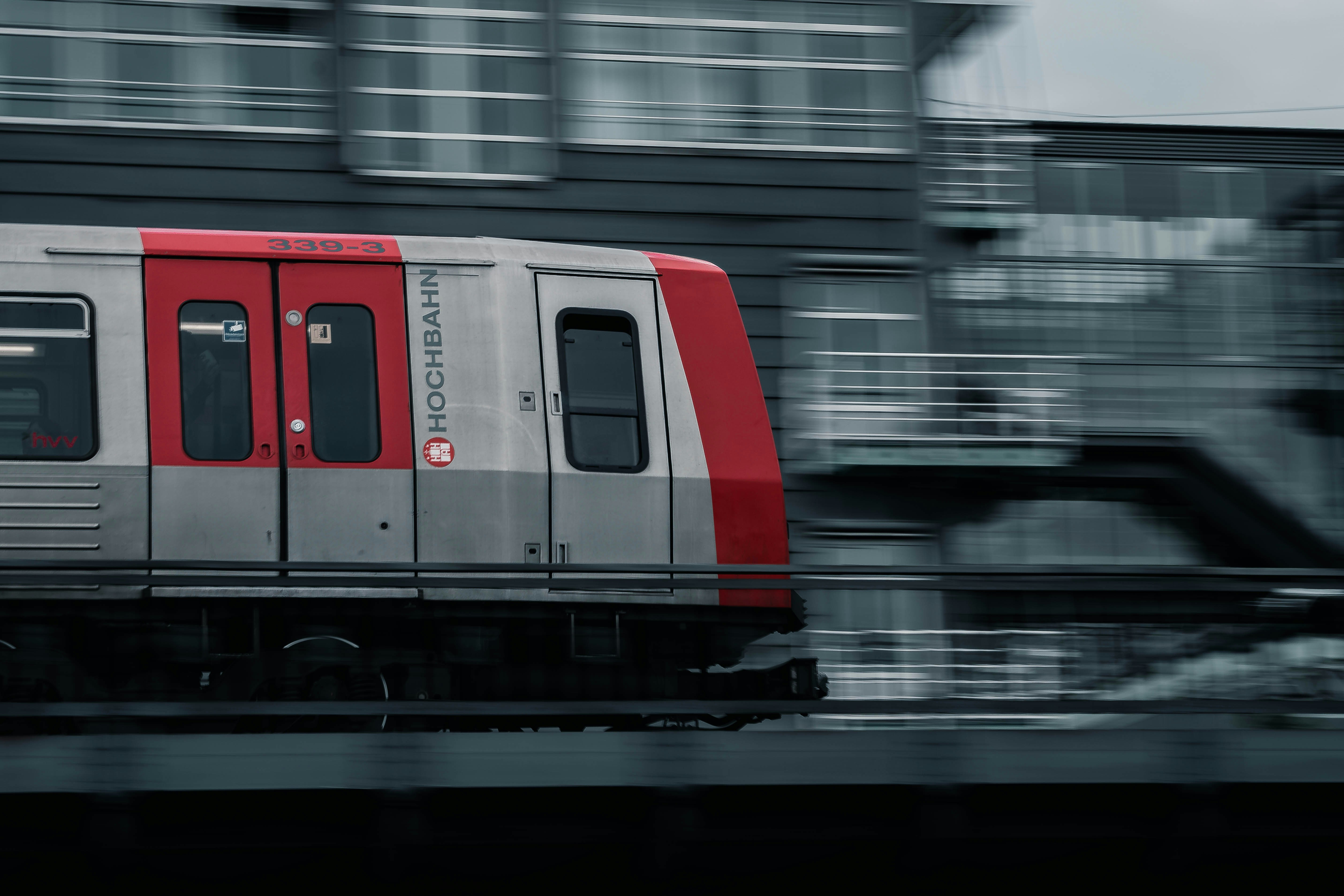 a red and silver train traveling past a tall building