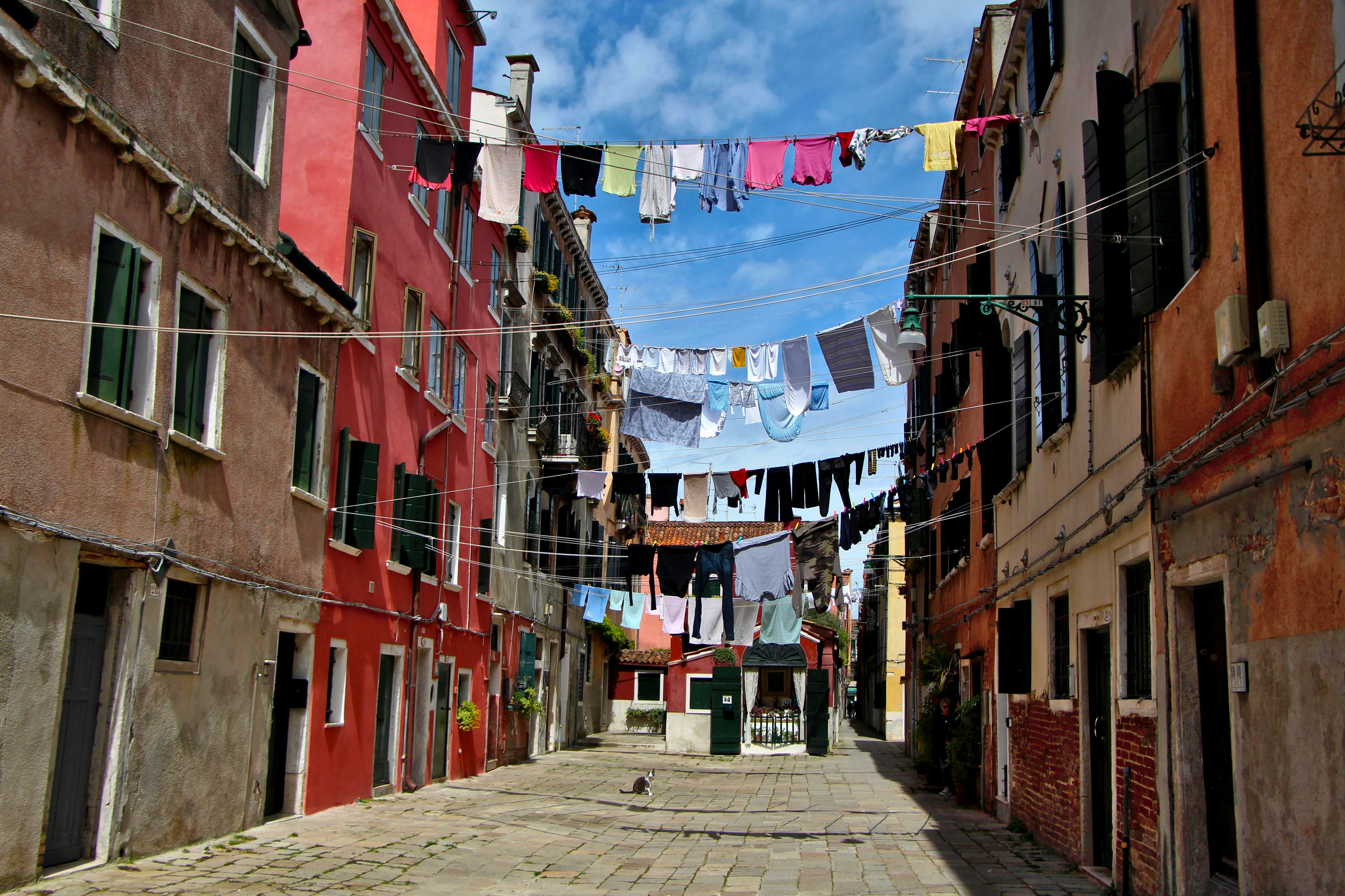 a narrow street with clothes hanging on a line, how to dry in venice