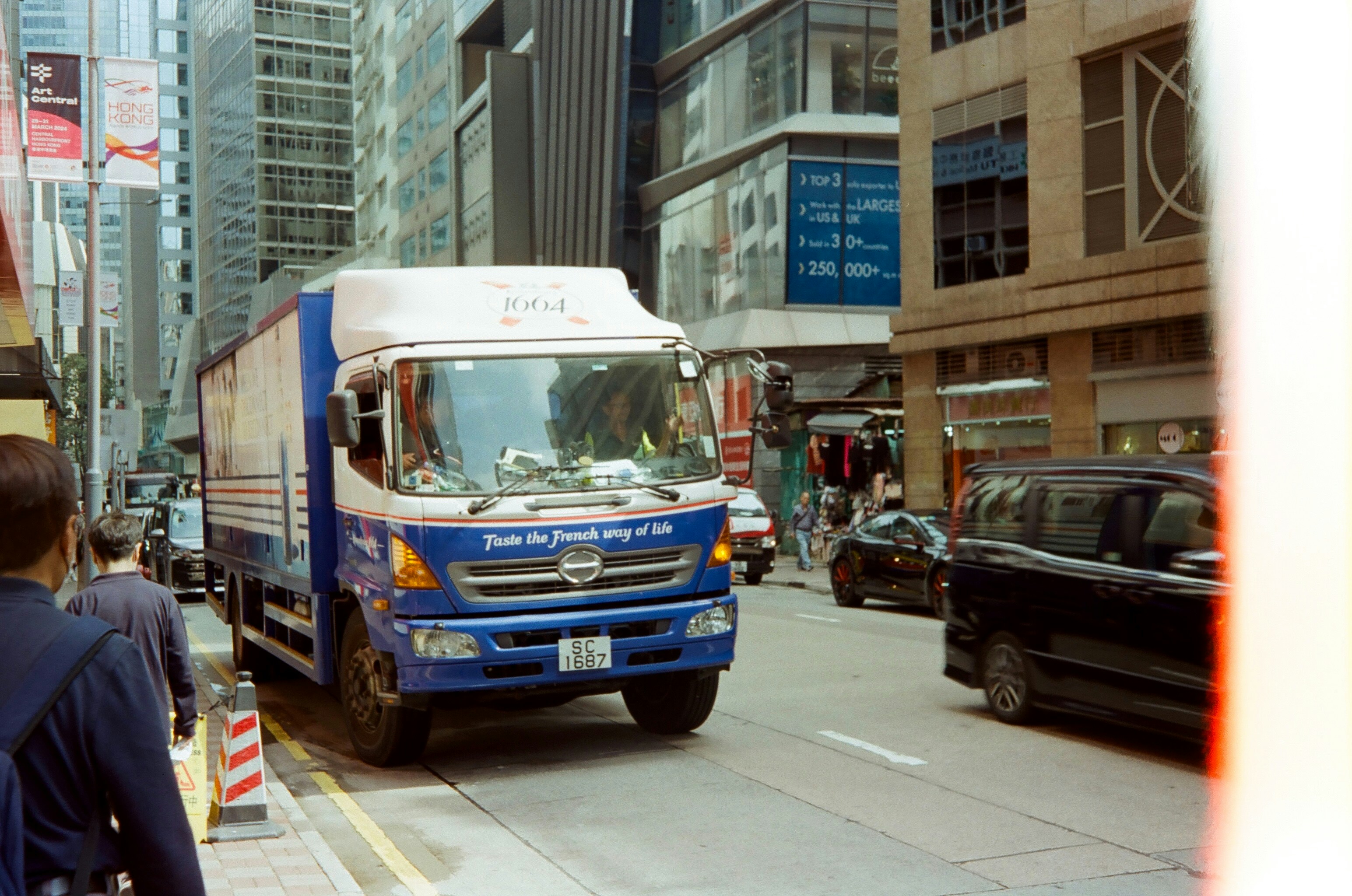 a blue and white truck driving down a street next to tall buildings