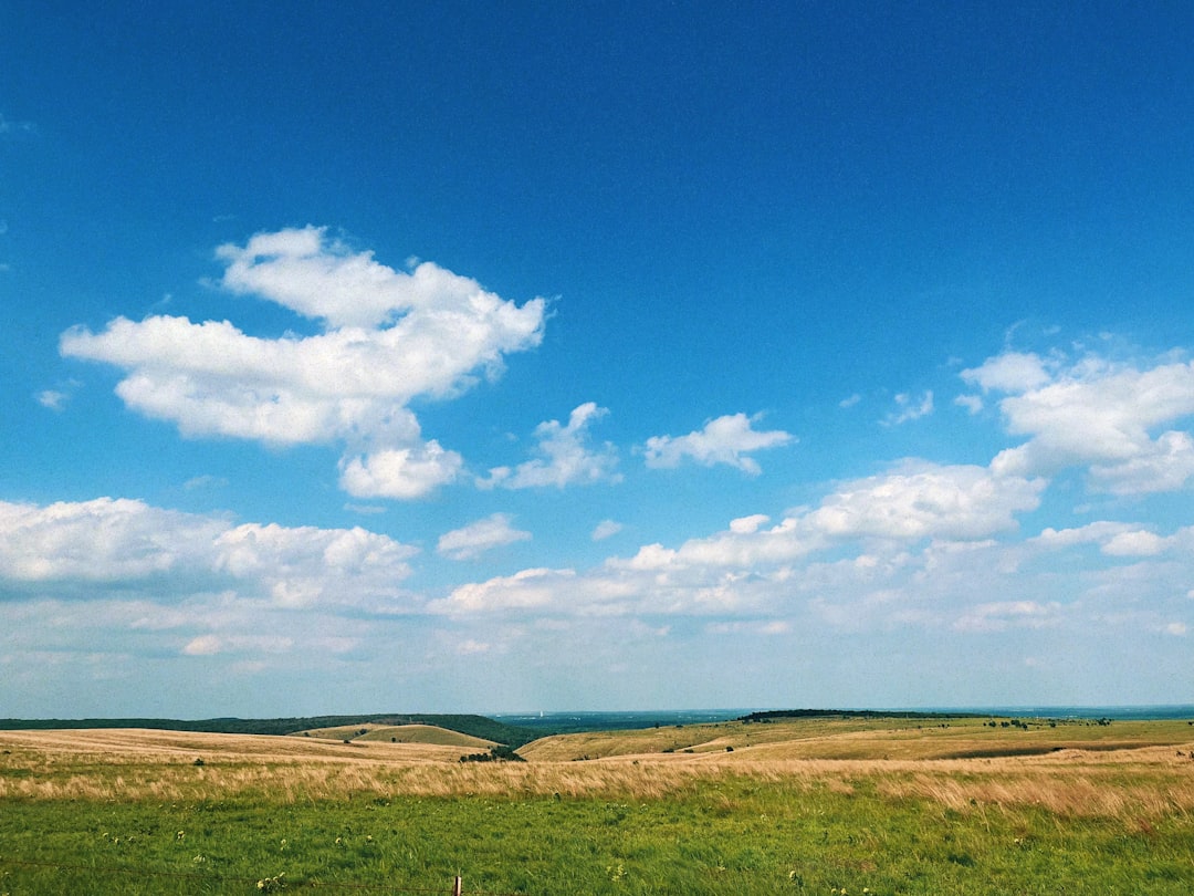 a green field with a few clouds in the sky,