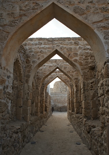 an archway in a stone building with a person standing in the doorway