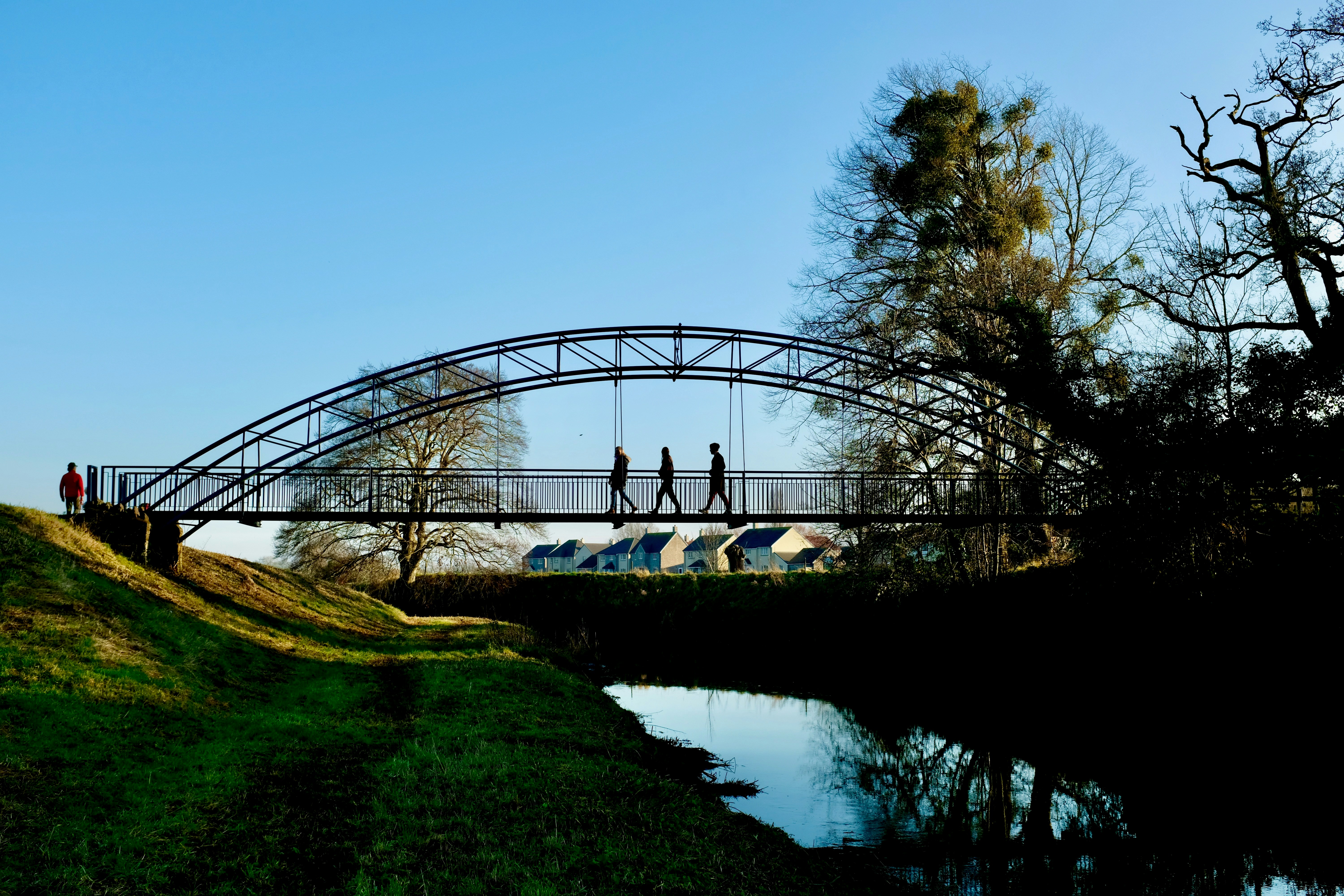 a couple of people walking across a bridge over a river
