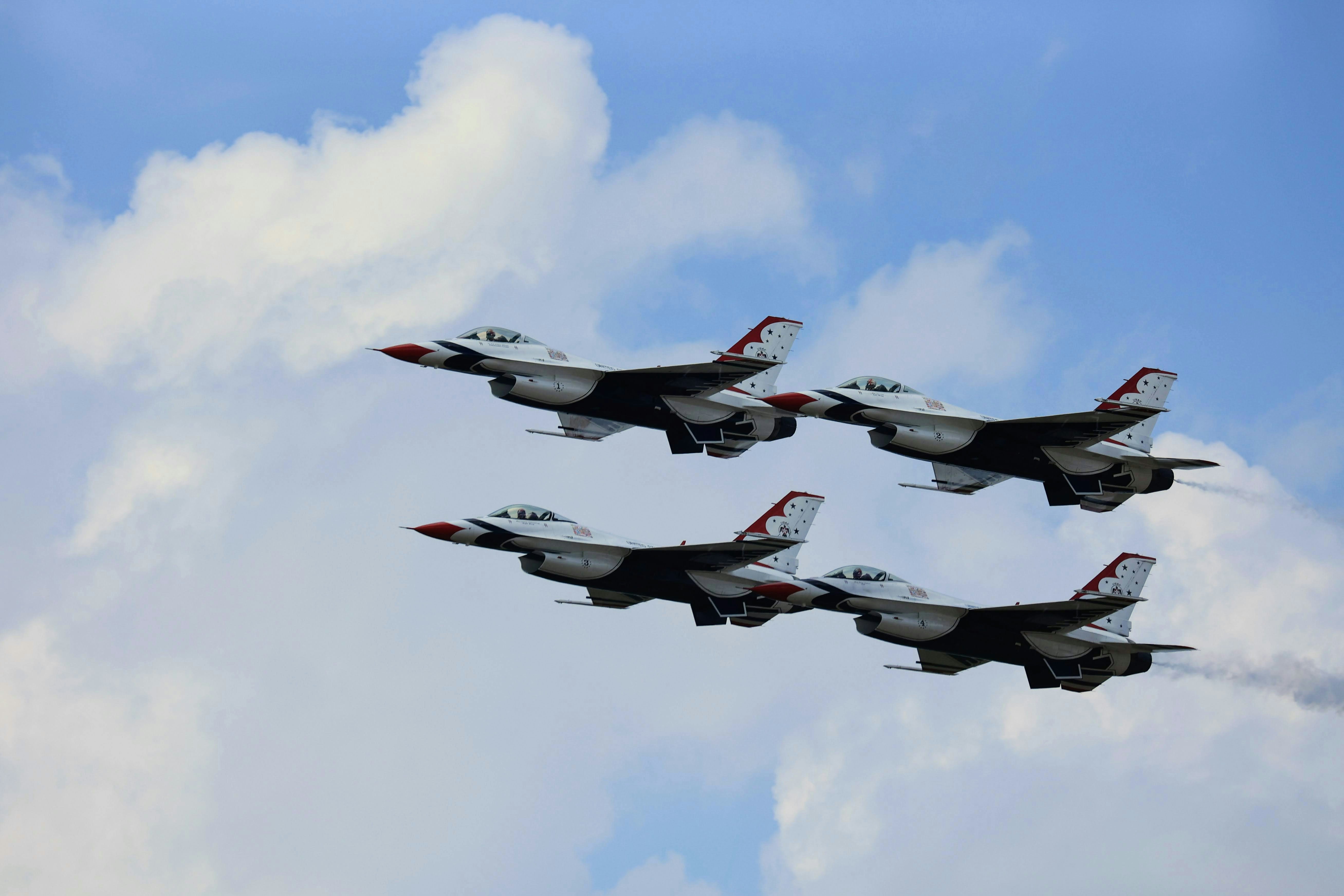 a group of fighter jets flying through a cloudy sky