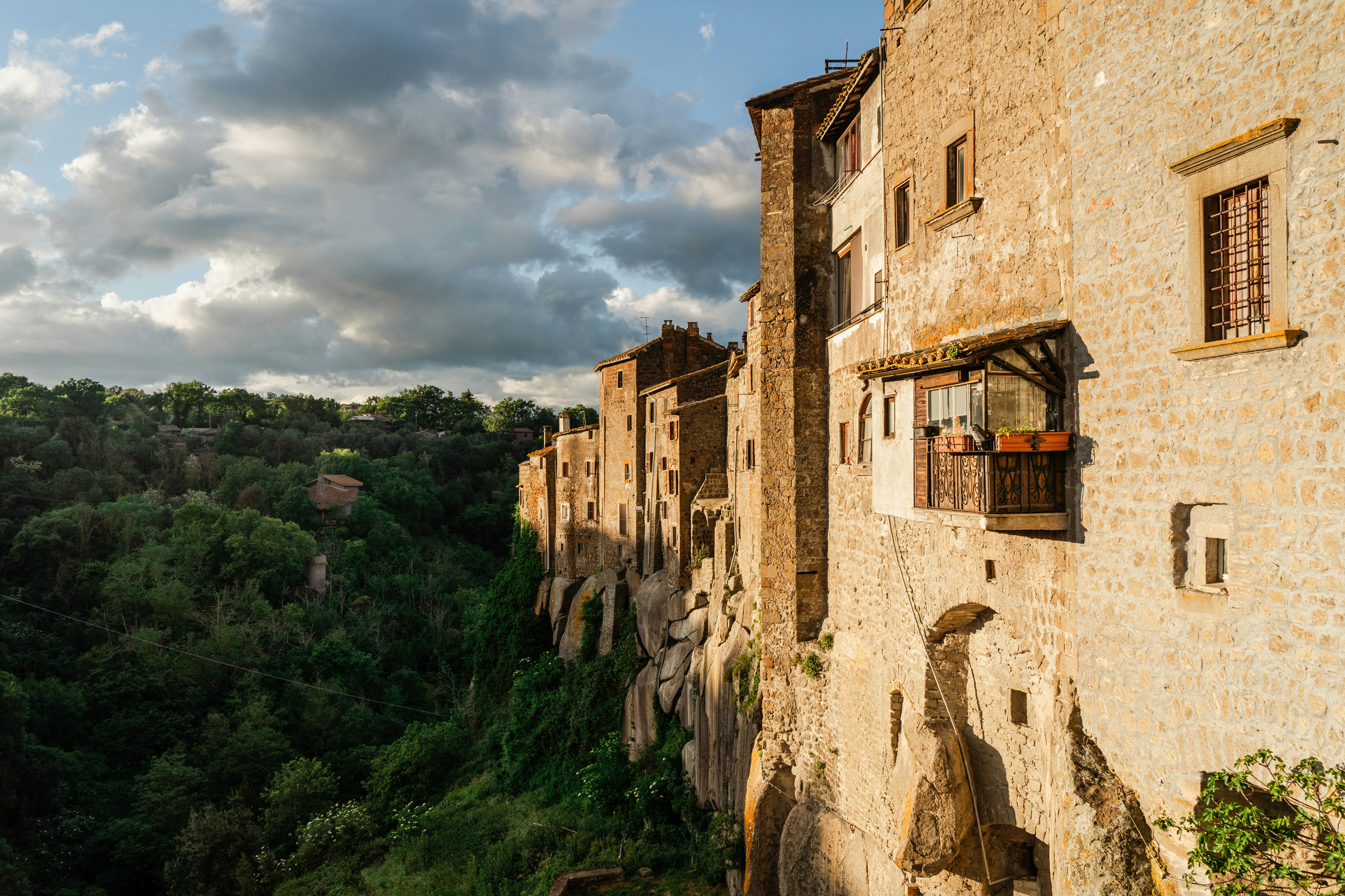 a stone building with a balcony on the side of it, The city walls of Vitorchiano, Italy, at sunset.