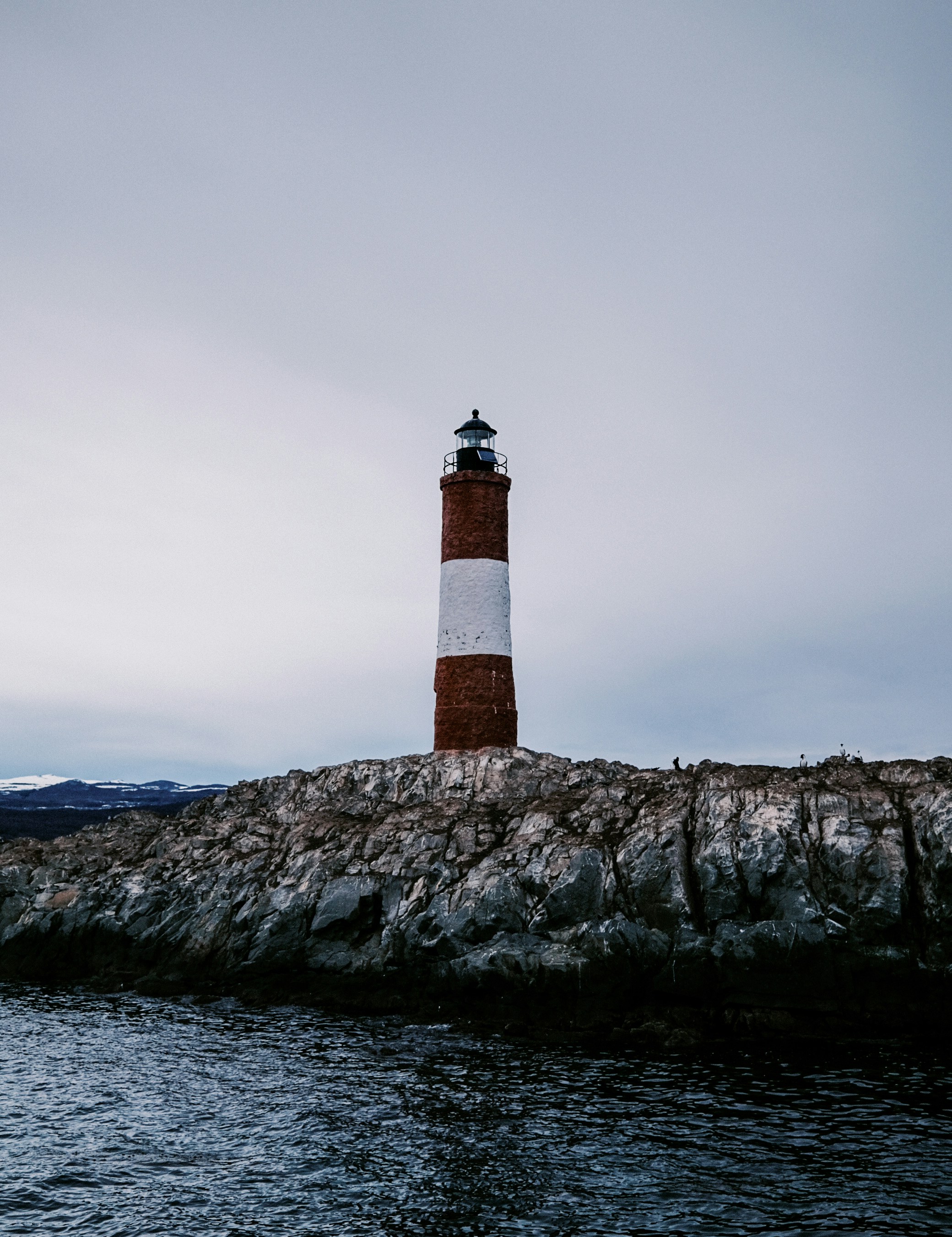 a red and white light house sitting on top of a rock