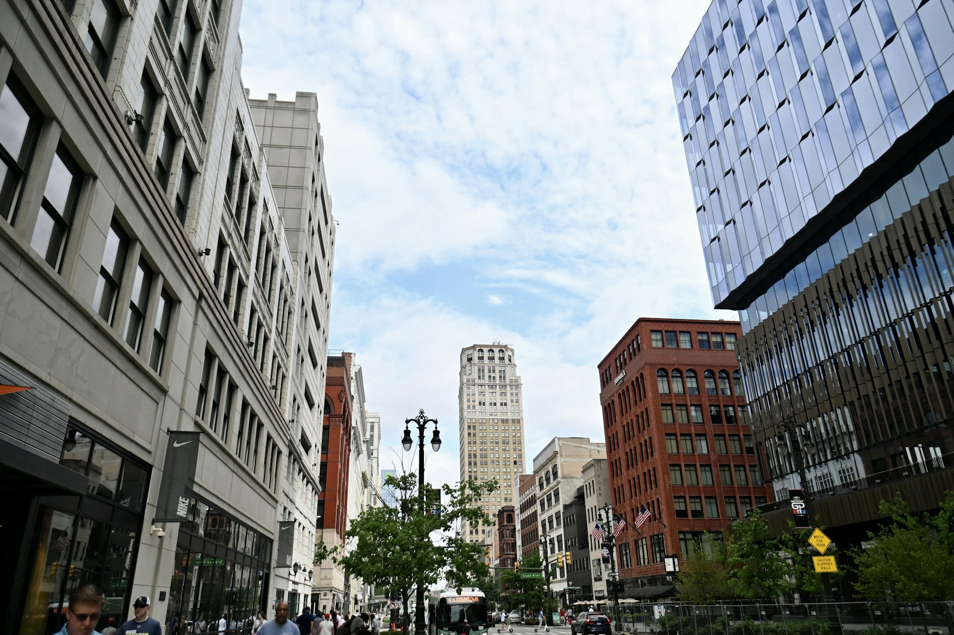 a group of people walking down a street next to tall buildings