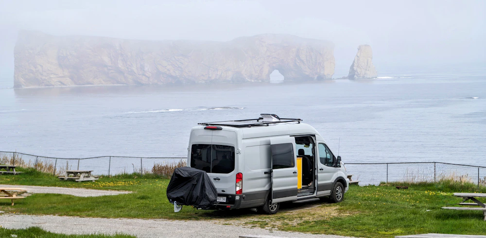 A camper van on a clifftop above Percé Rock in the fog