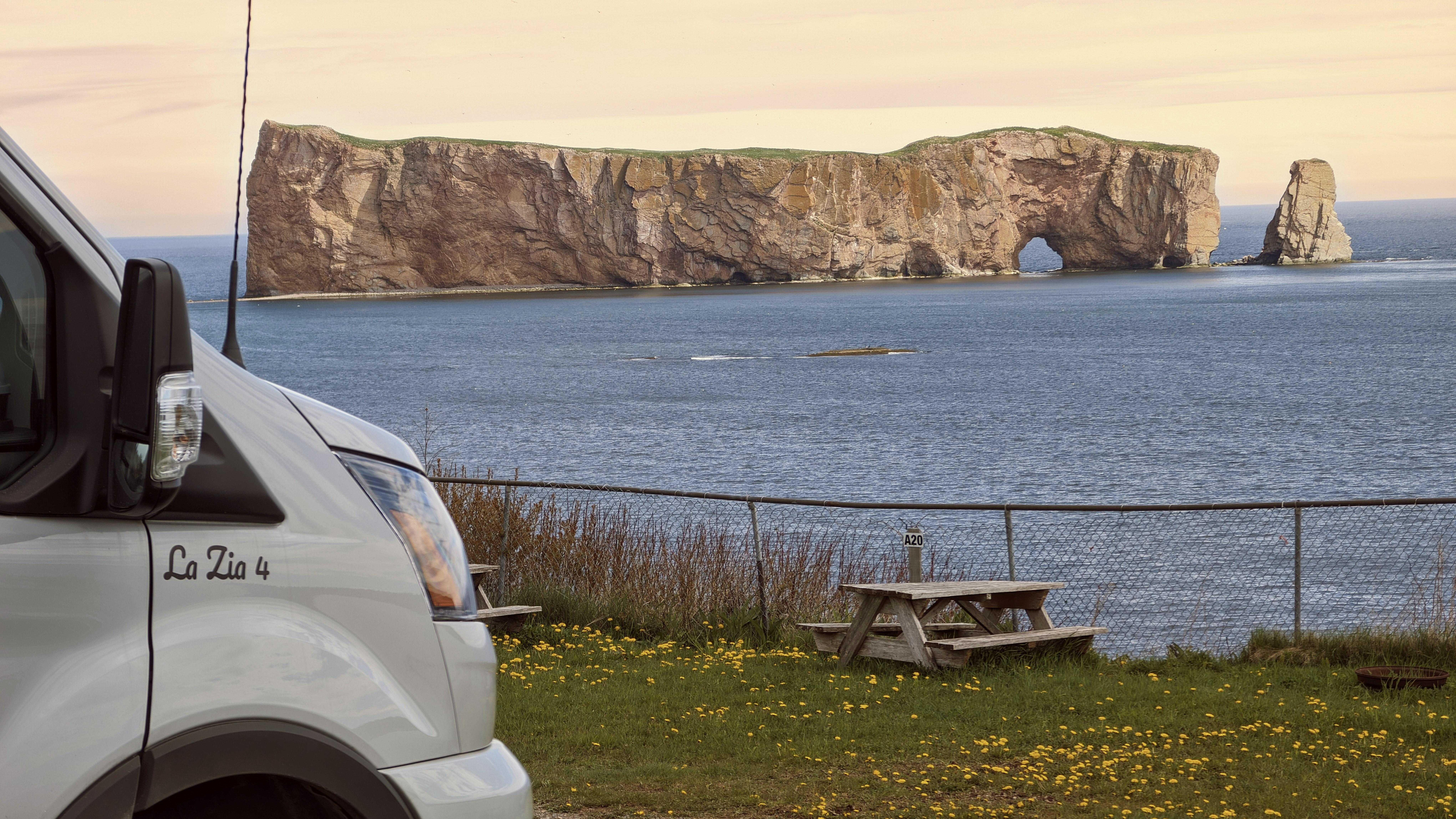 Una furgoneta aparcada junto a una mesa de picnic cerca del océano