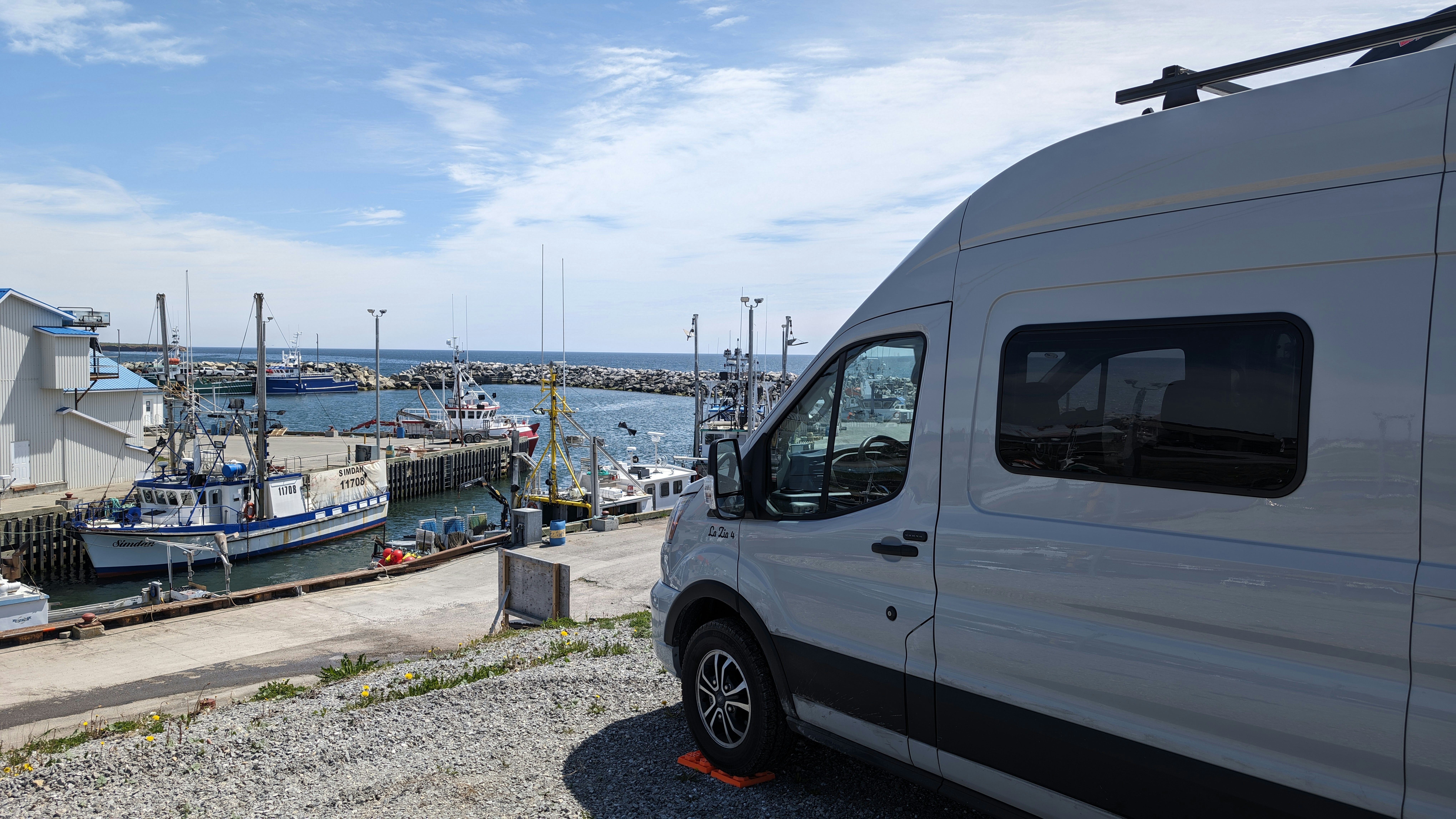 Una furgoneta aparcada junto a un muelle con botes en el agua