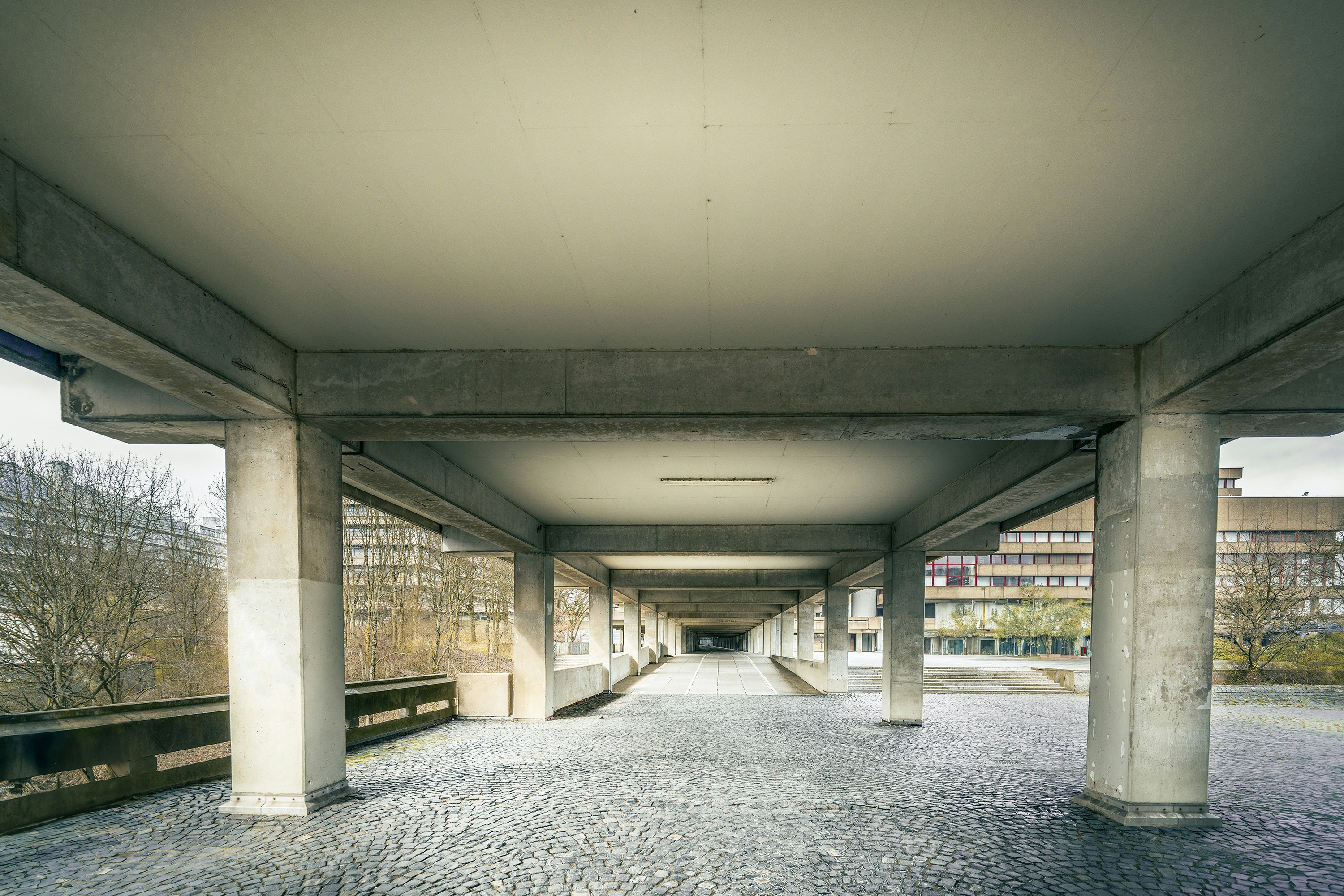 an empty walkway in a large building with columns