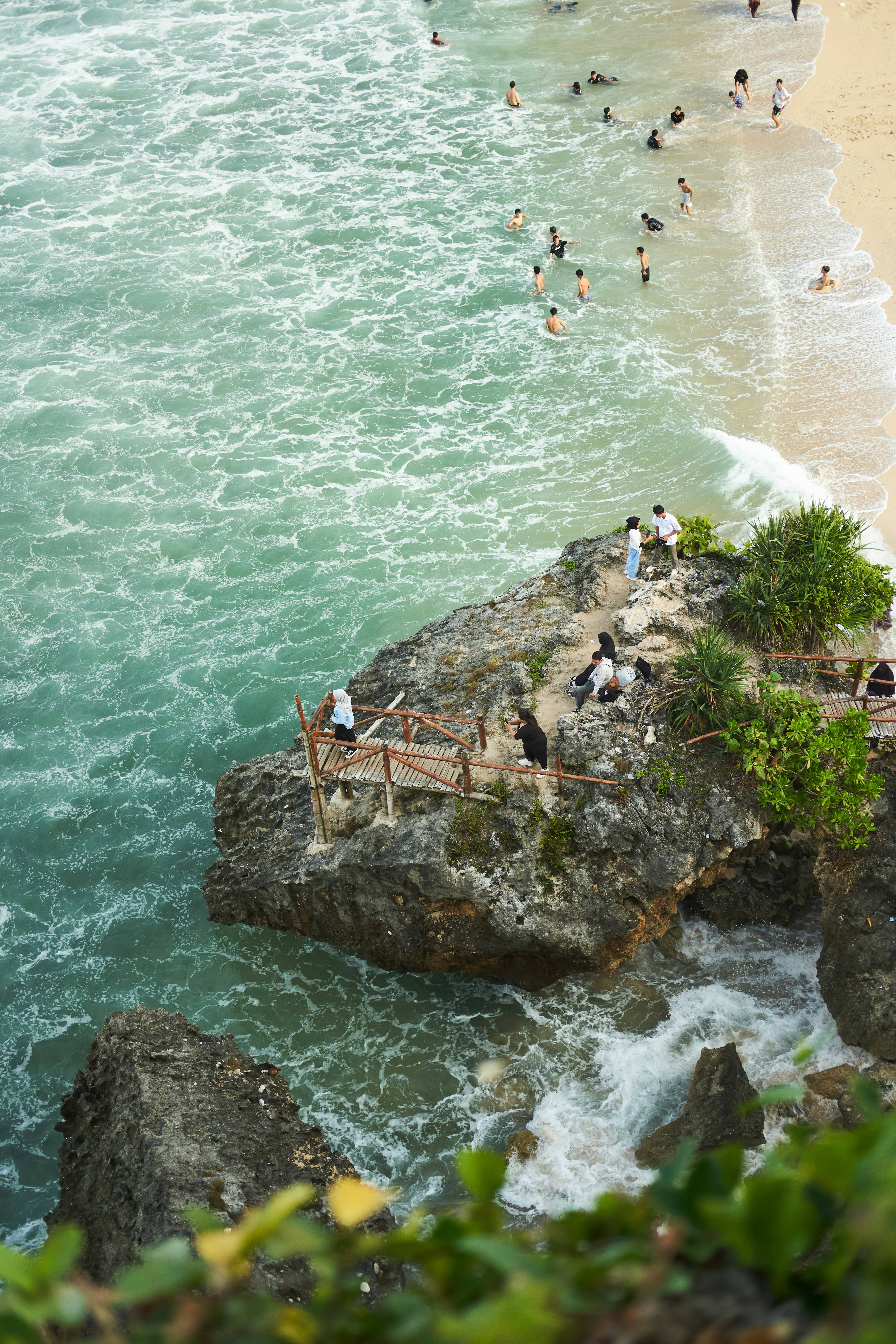 a group of people standing on top of a cliff next to the ocean