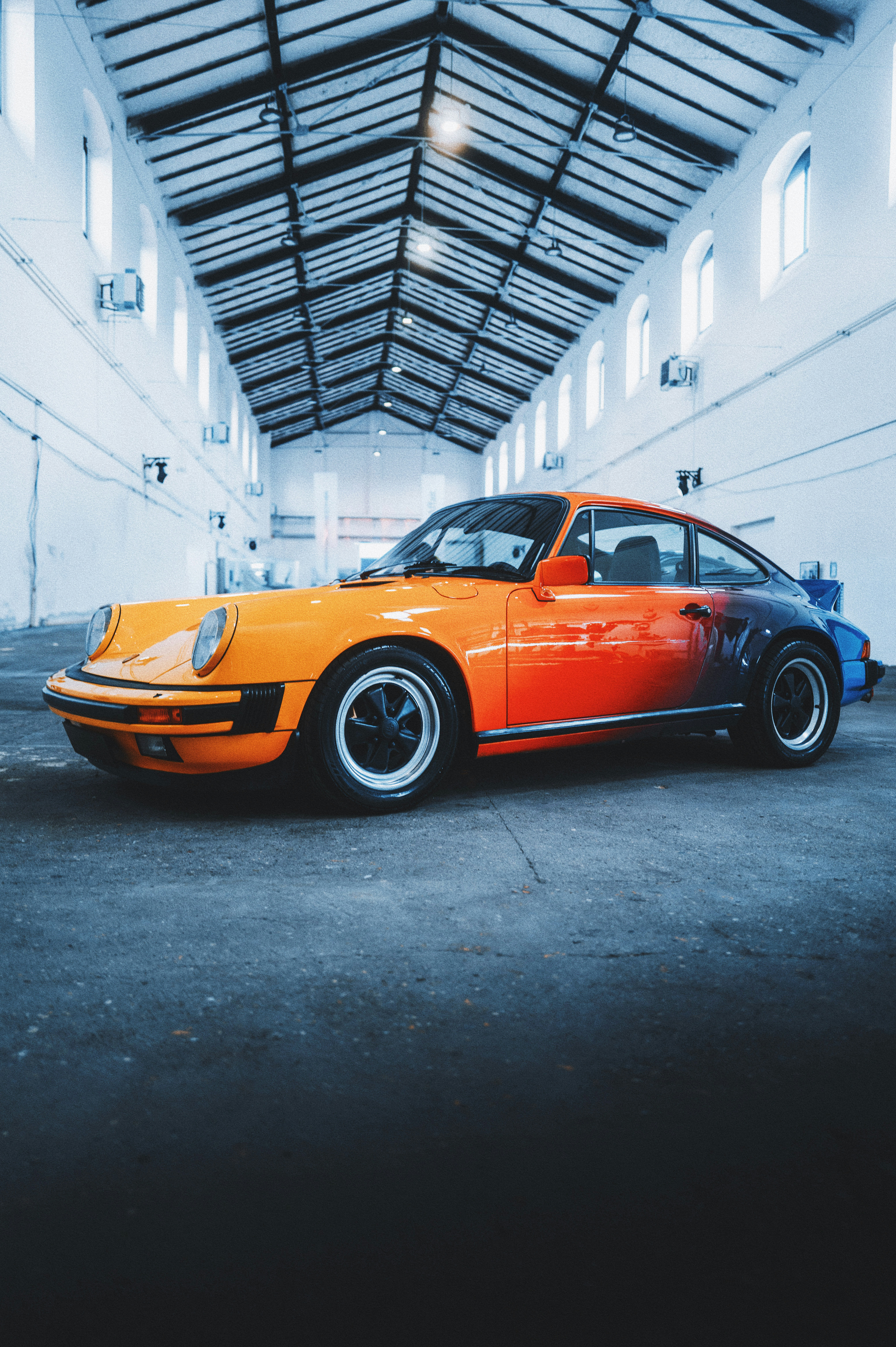 an orange and blue porsche parked in a garage