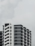 an airplane flying over a tall building in a cloudy sky
