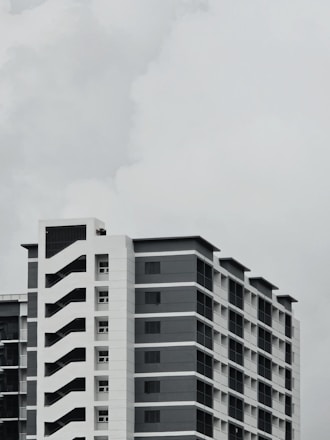 an airplane flying over a tall building in a cloudy sky