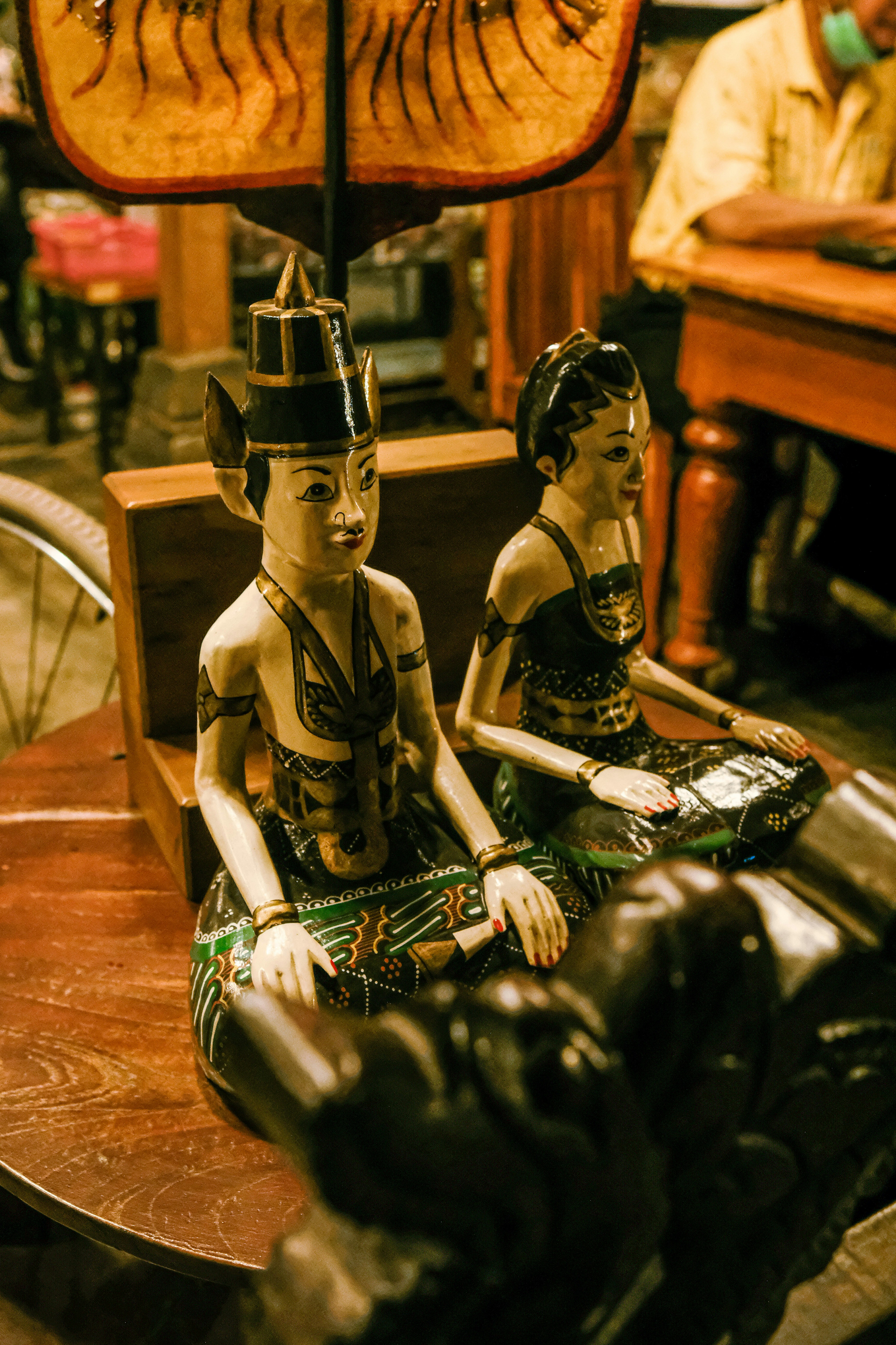a couple of statues sitting on top of a wooden bench