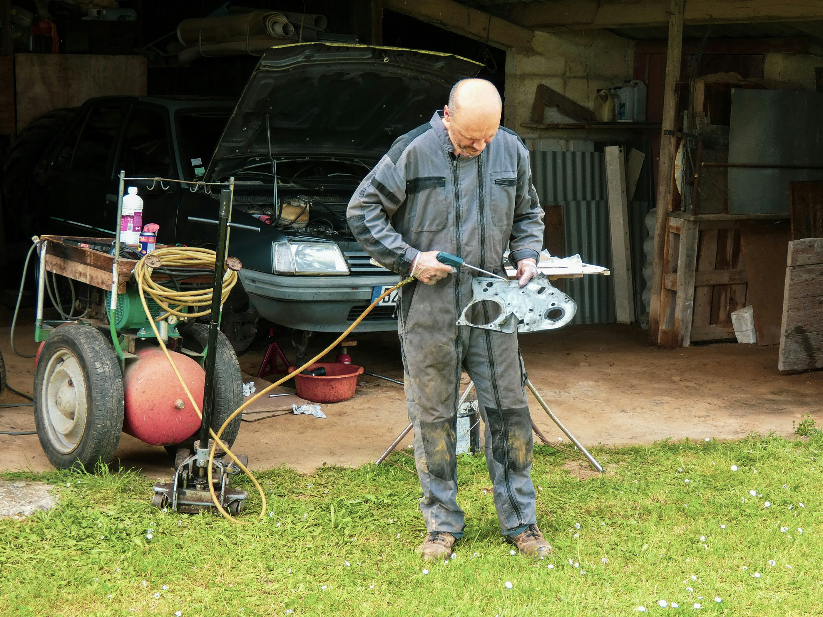 a man in overalls working on a piece of metal