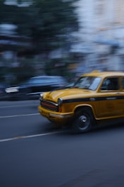 a yellow taxi driving down a street next to tall buildings