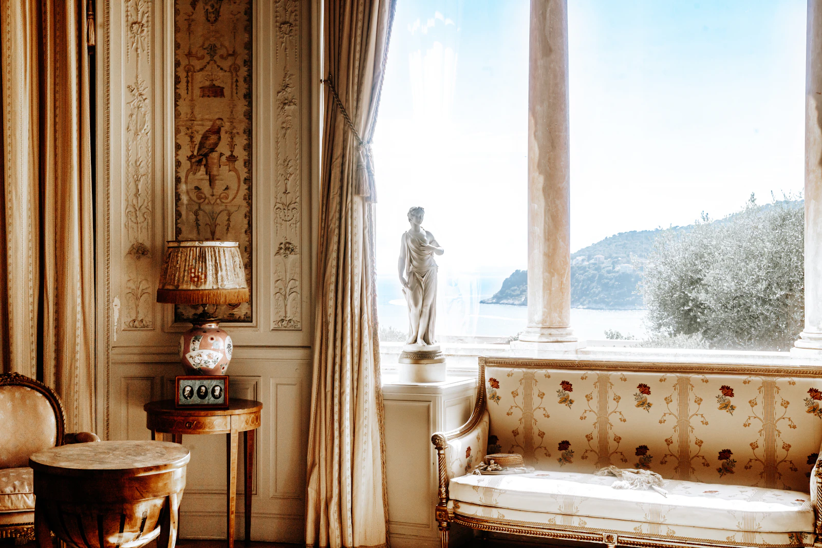 Gilded drawing room with a marble statue by a tall window
