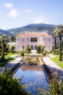 a large pink house with a pond in front of it