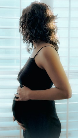a pregnant woman standing in front of a window