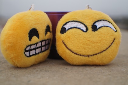 a pair of yellow smiley face stuffed toys