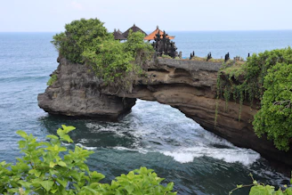 a rocky cliff with a bridge over a body of water