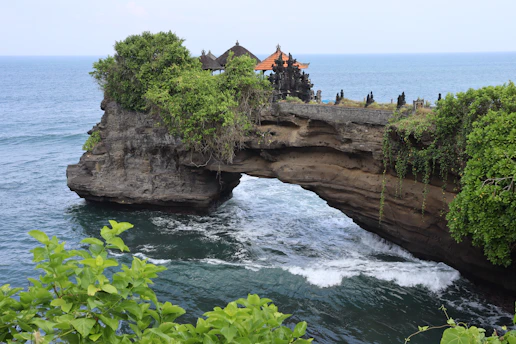 a rocky cliff with a bridge over a body of water