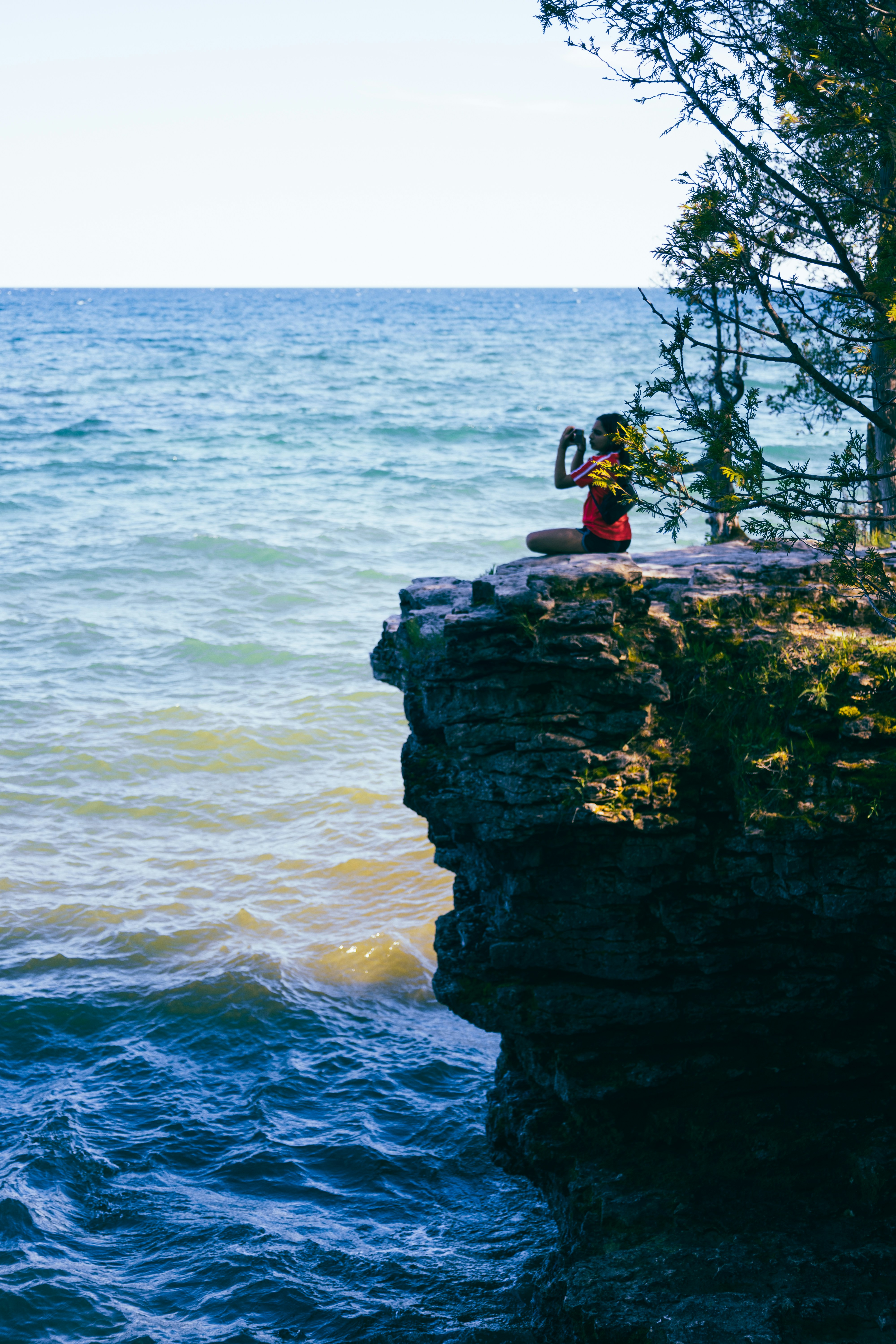 a person taking a picture of the ocean from a cliff