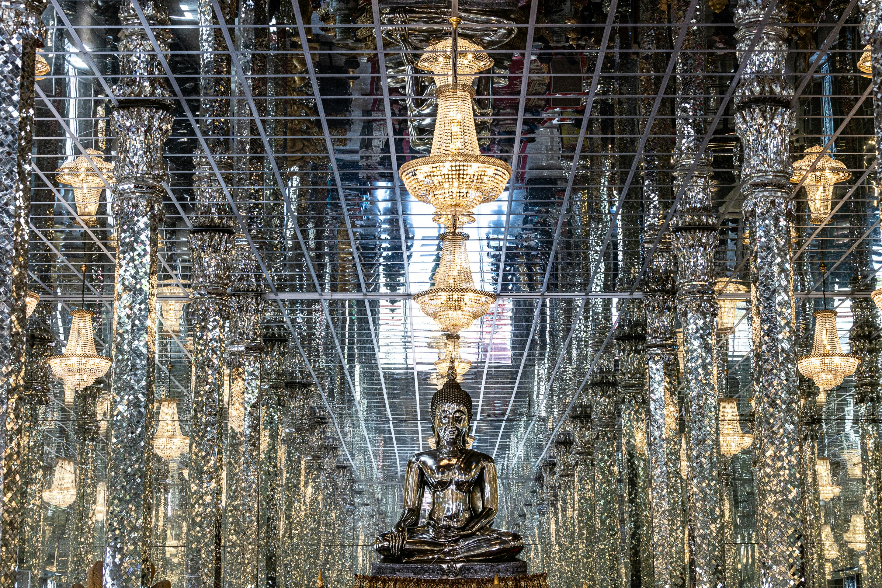 a large buddha statue sitting in a room filled with lots of lights, 