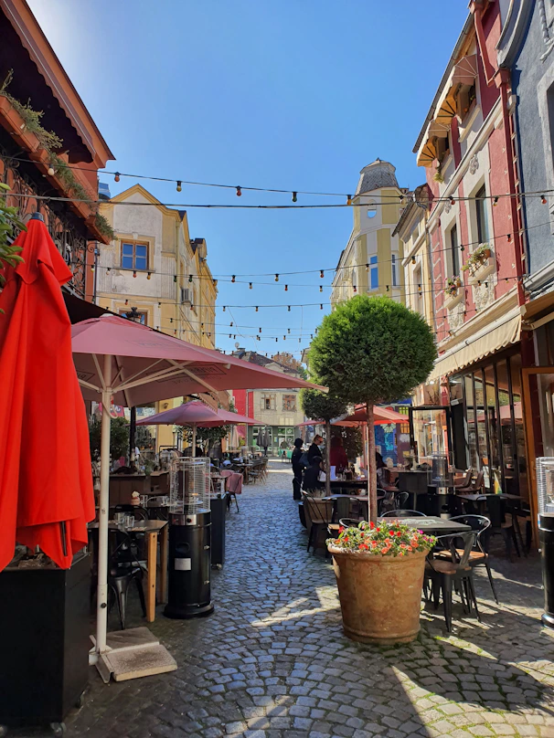 a cobblestone street lined with tables and umbrellas