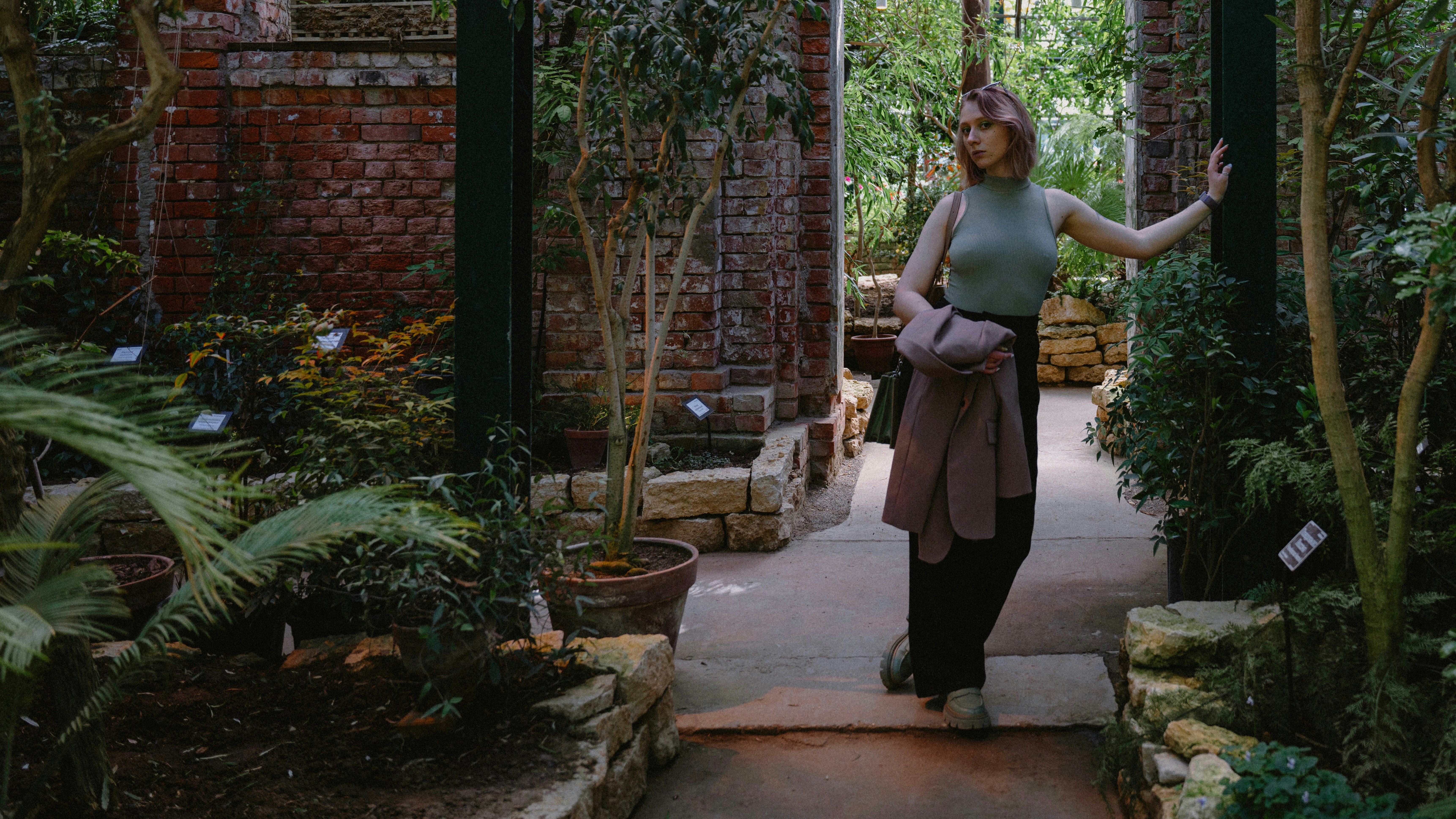 a woman is standing in a garden area