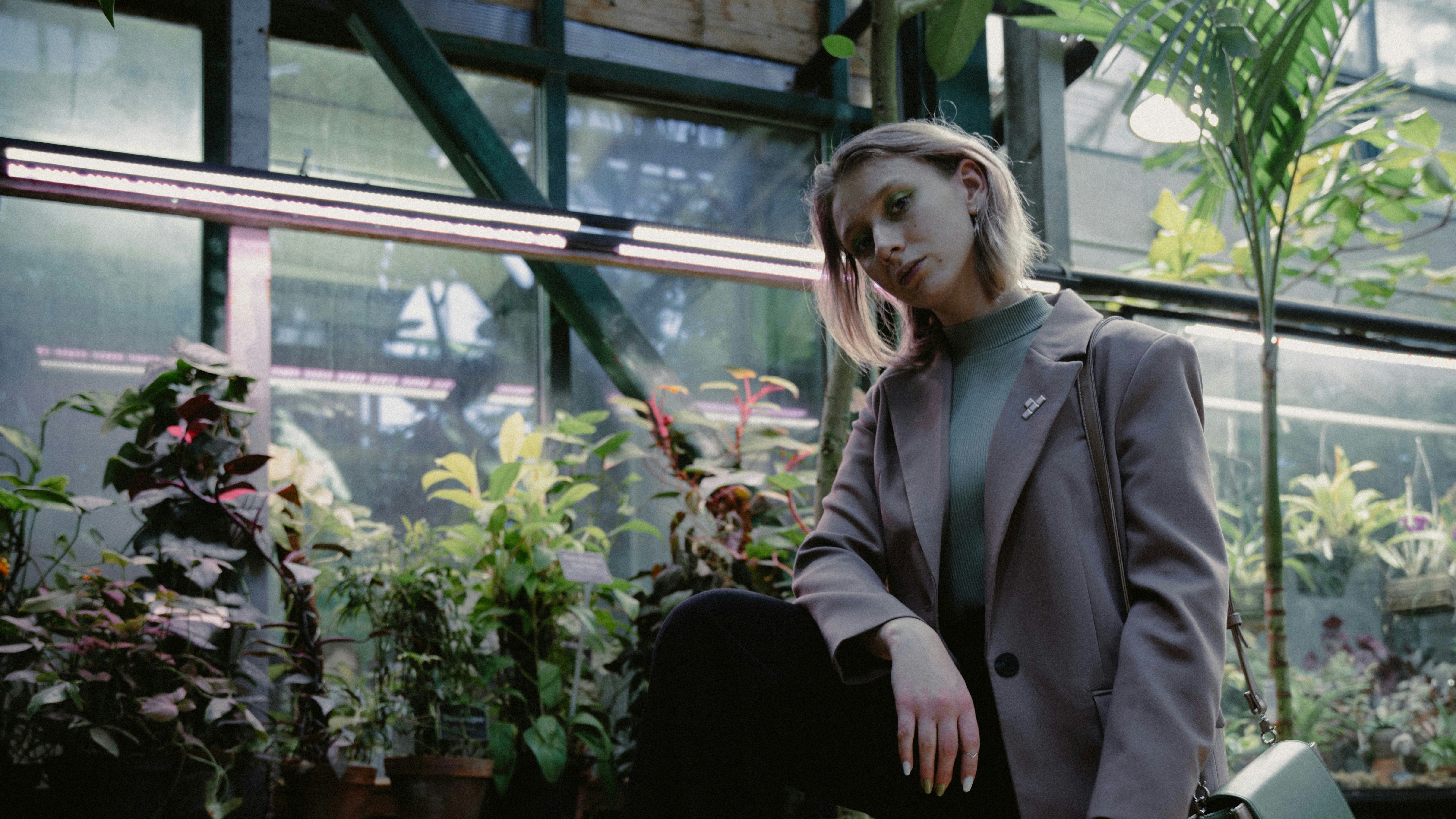 a woman standing in front of a greenhouse filled with plants