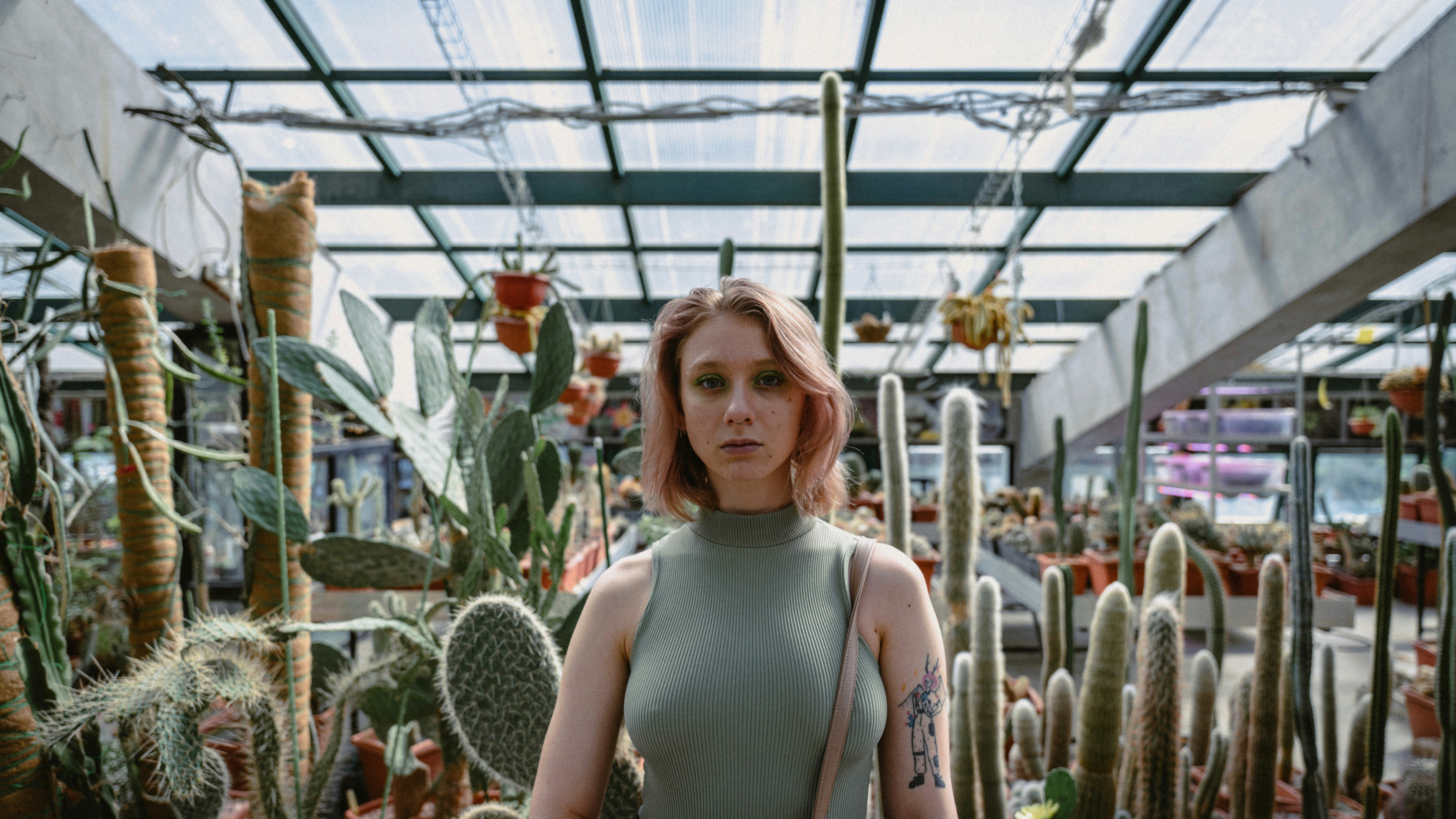 a woman standing in a greenhouse surrounded by cacti