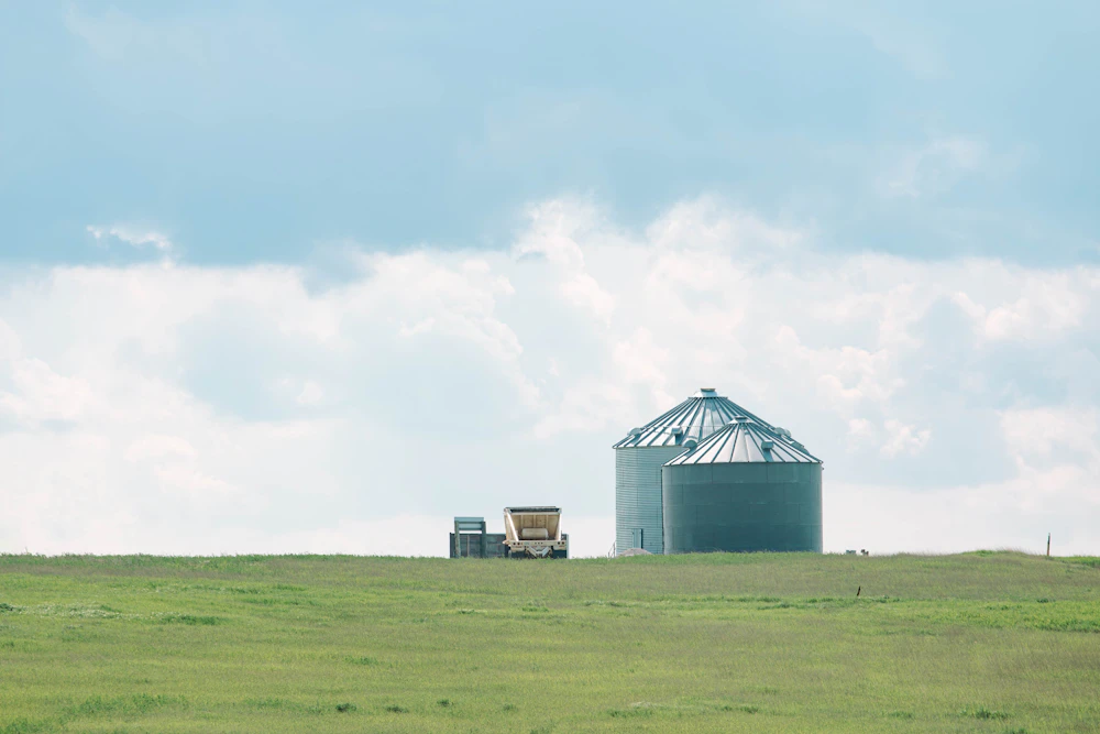 A farm with a grain silo and a tractor in the foreground
