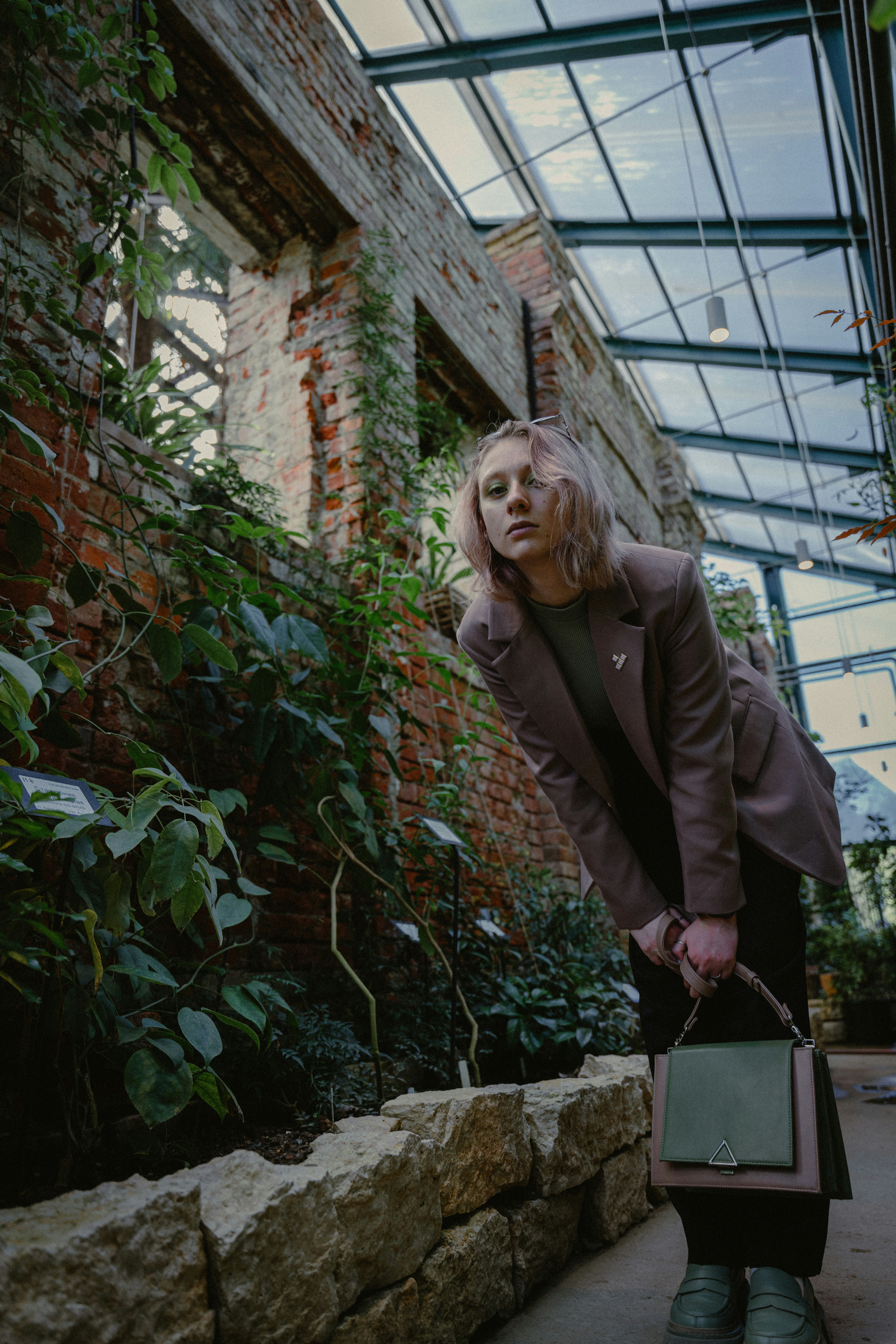 a woman holding a suitcase in a greenhouse