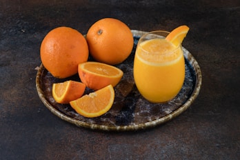 a plate of oranges and a glass of orange juice