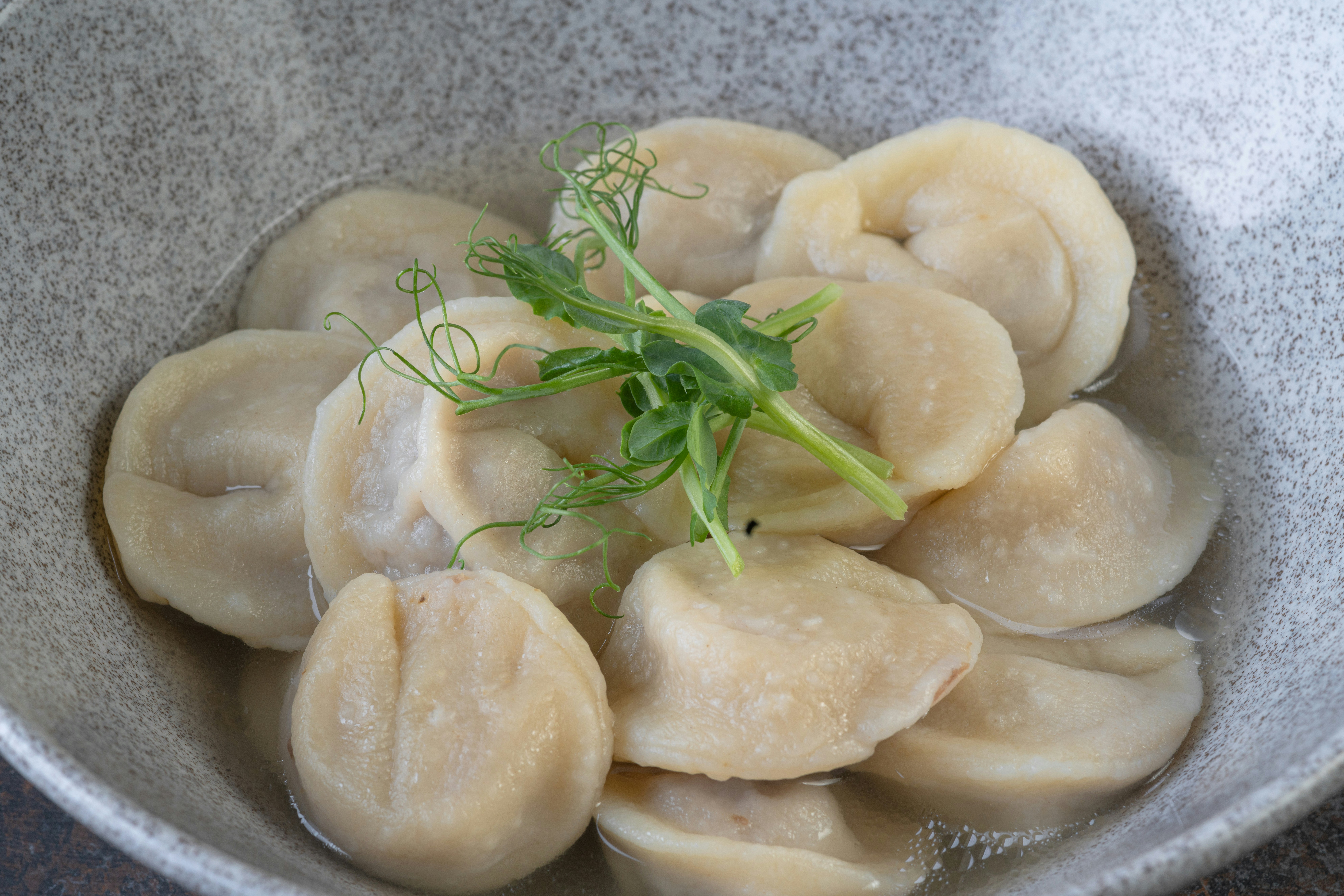 a bowl of dumplings with a sprig of parsley