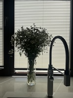 a vase of flowers sitting on a kitchen counter next to a faucet