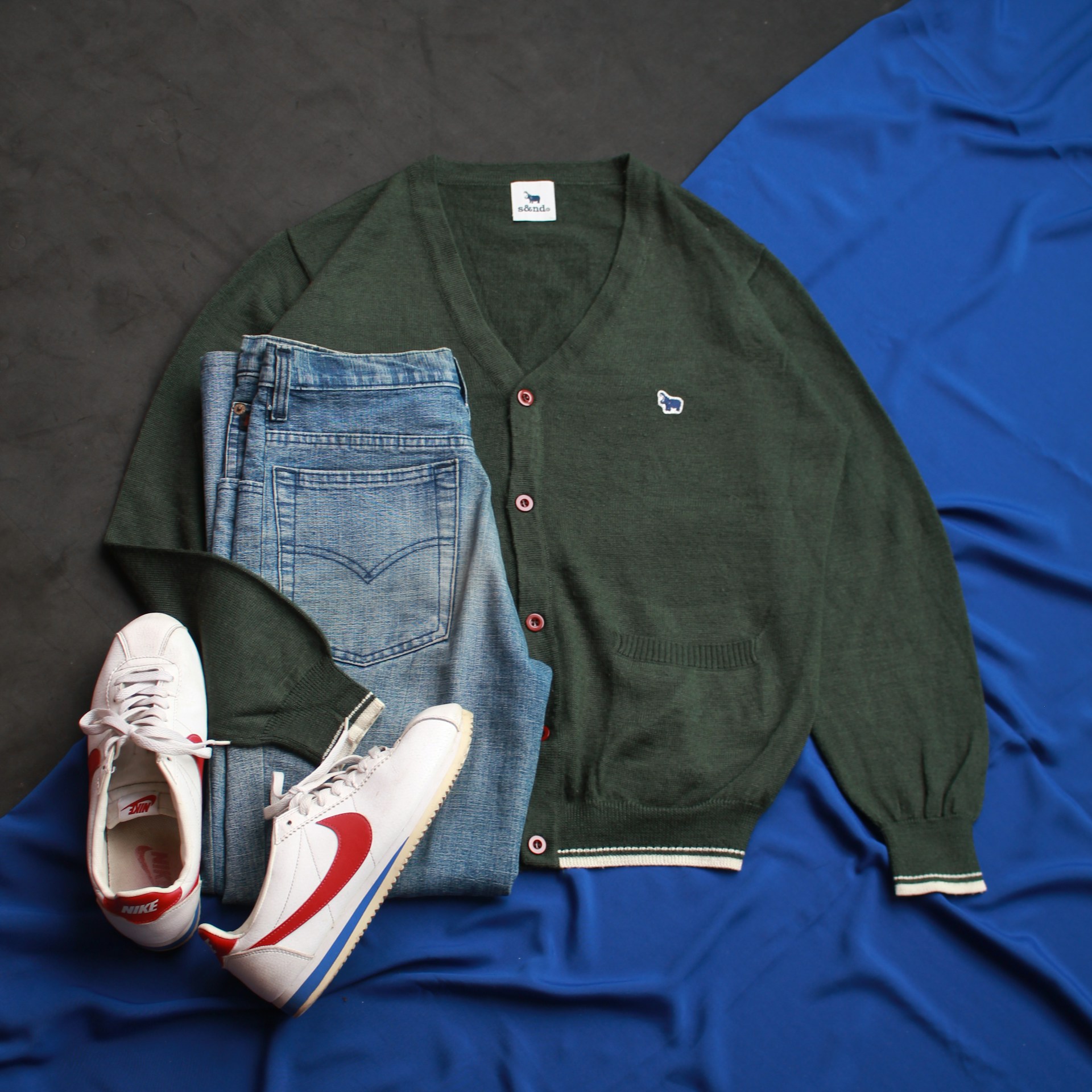 a pair of shoes, a sweater, and a pair of jeans lay on a