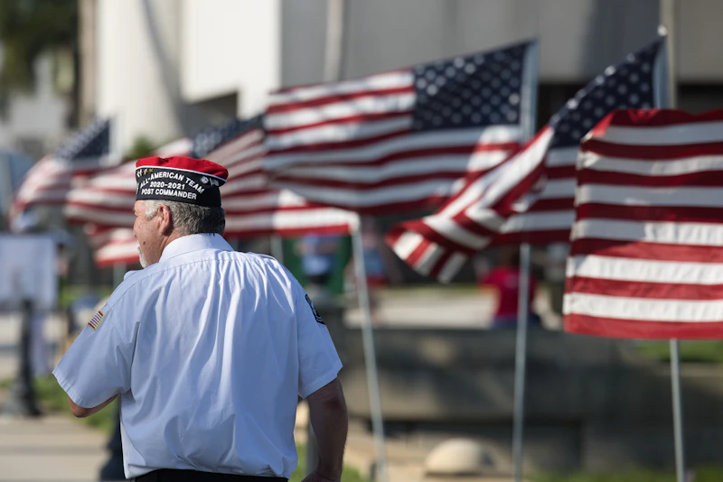 Veteran standing proudly in front of a row of American flags