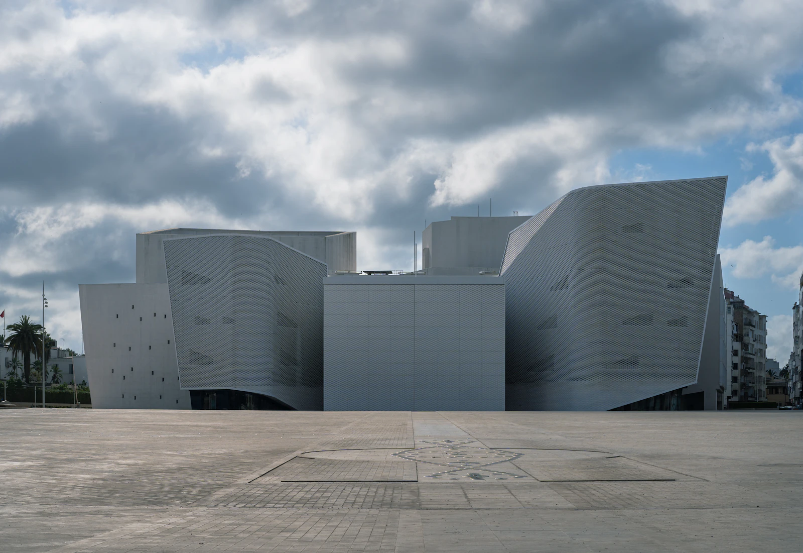 Immeuble résidentiel moderne avec parvis minéral, rappelant Enakhil.