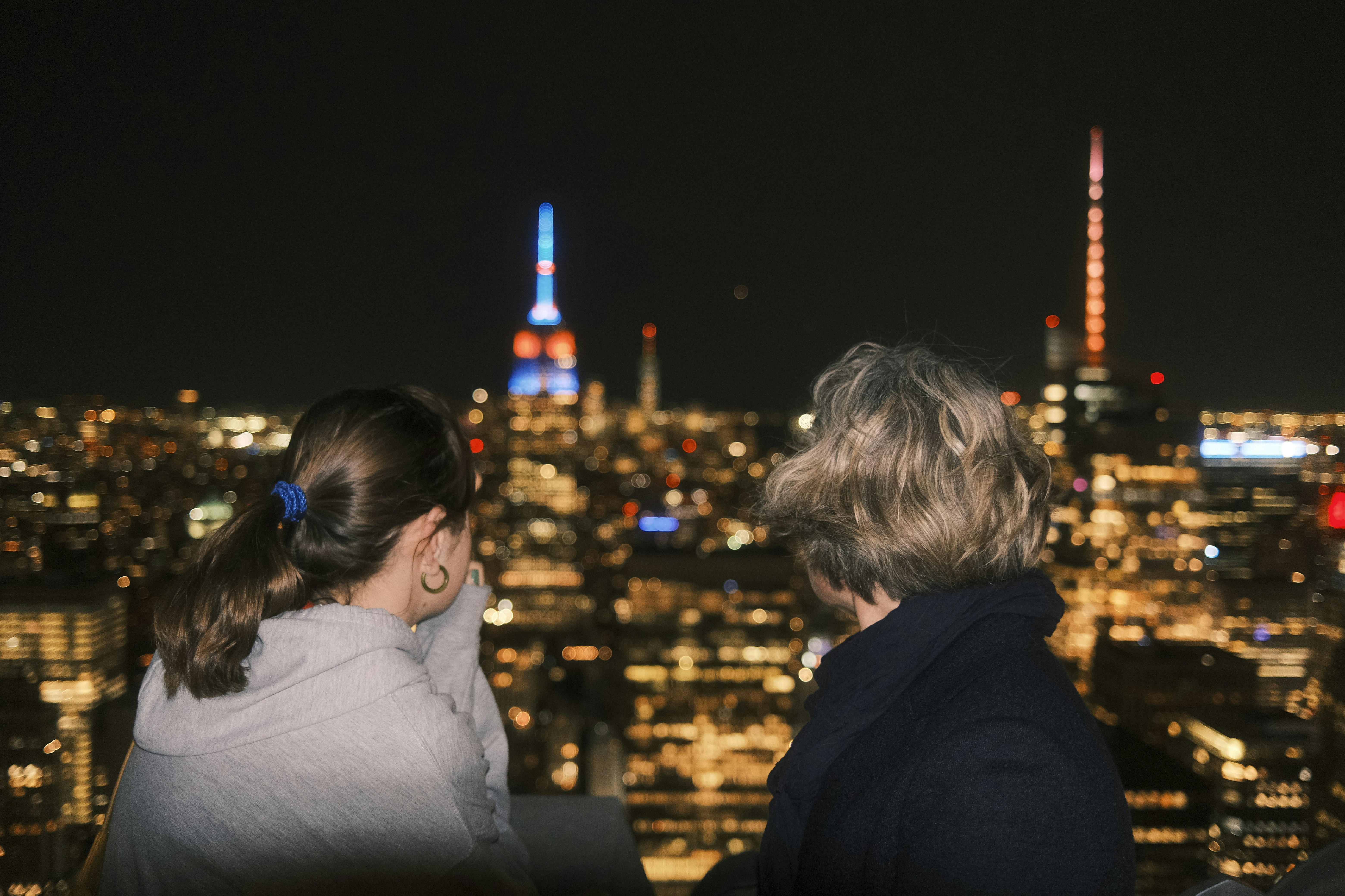a couple of women standing on top of a tall building
