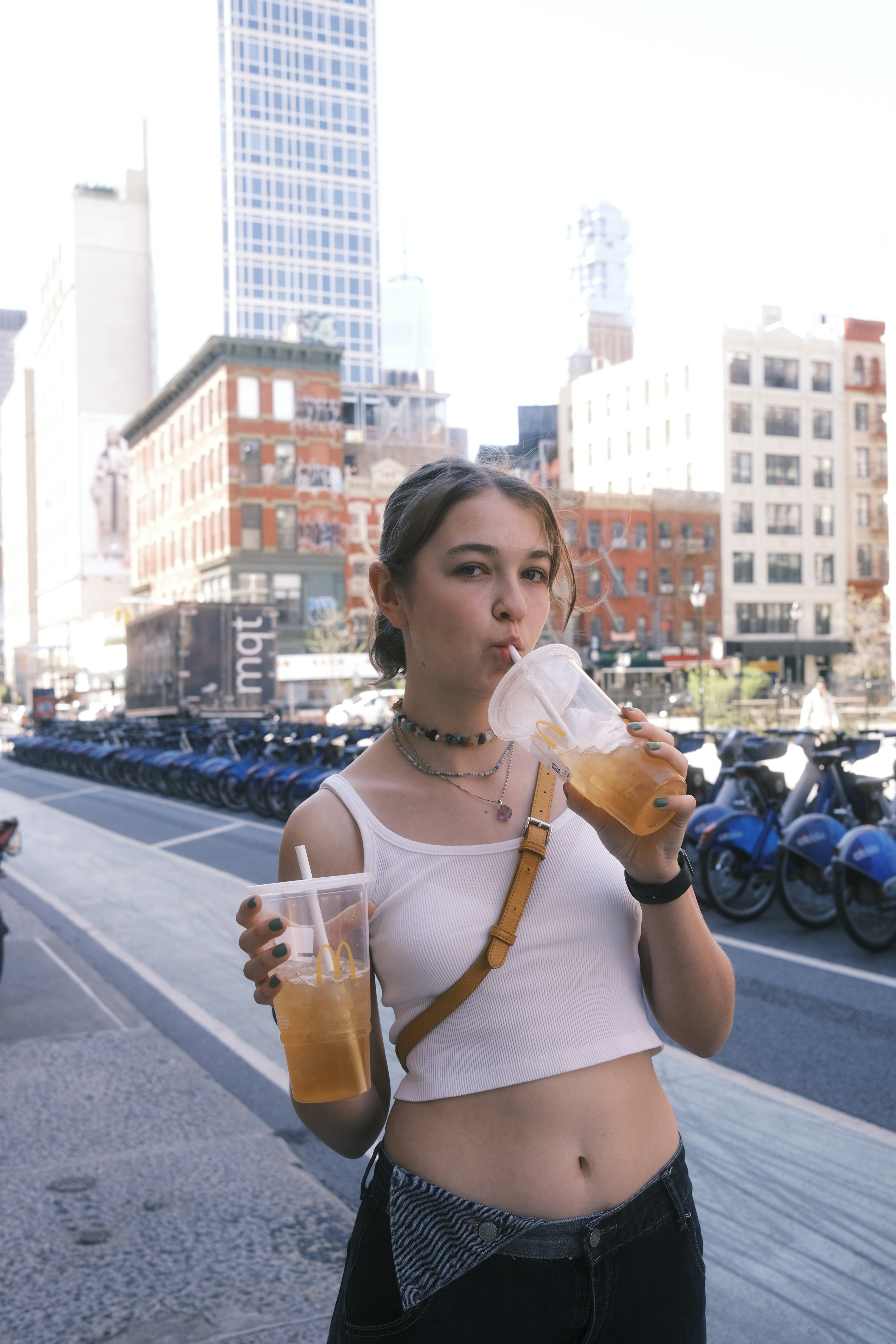 a woman standing on a street drinking a drink