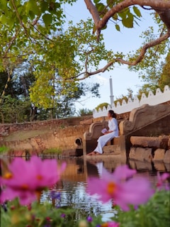 a woman sitting on a bench next to a body of water