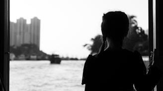 a woman looking out a window at a body of water